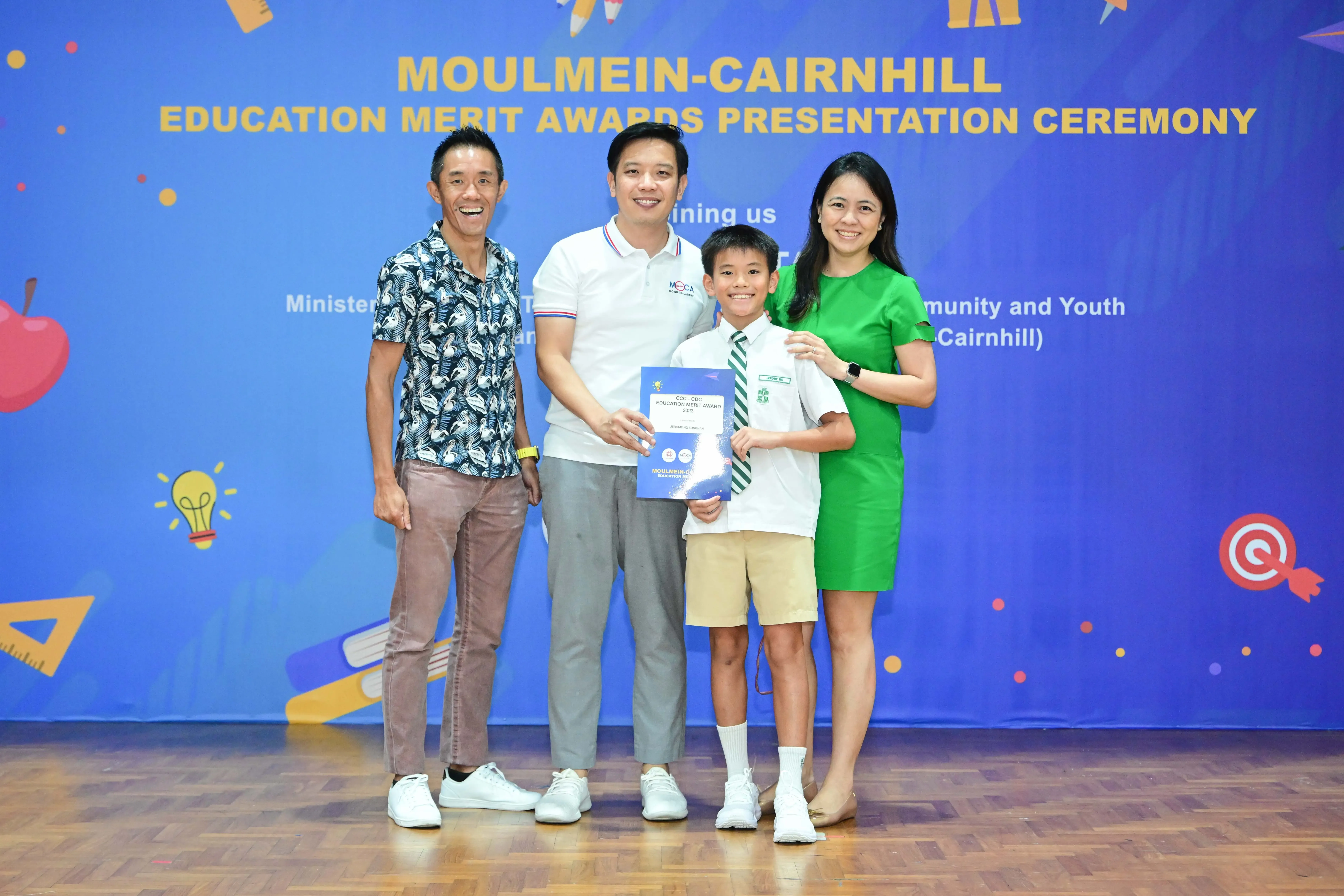 Three adults and a boy holding a certificate pose at the Moulmein-Cairnhill Education Merit Awards Ceremony.