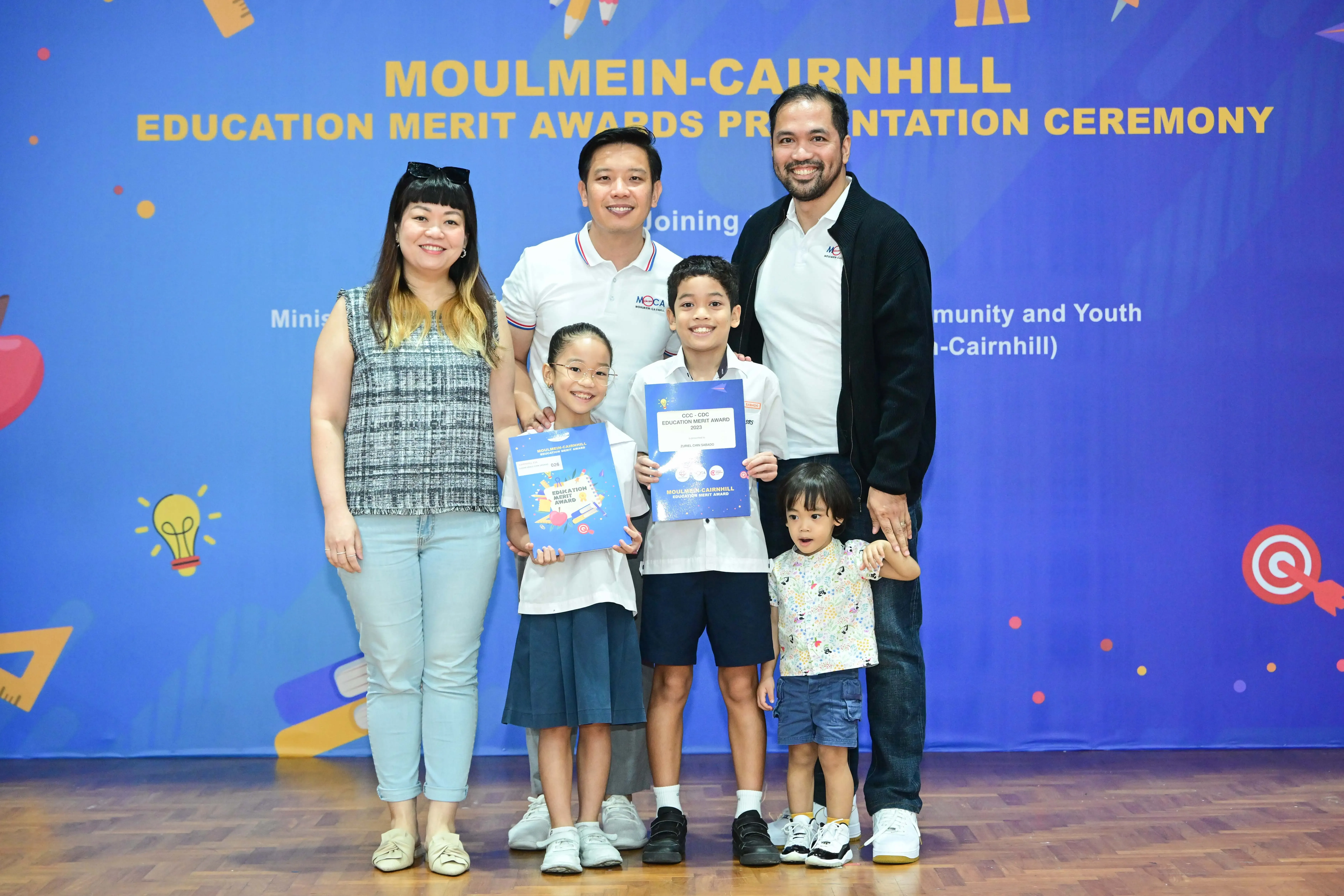 Family of five posing with award certificates at Moulmein-Cairnhill Education Merit Awards Presentation Ceremony.