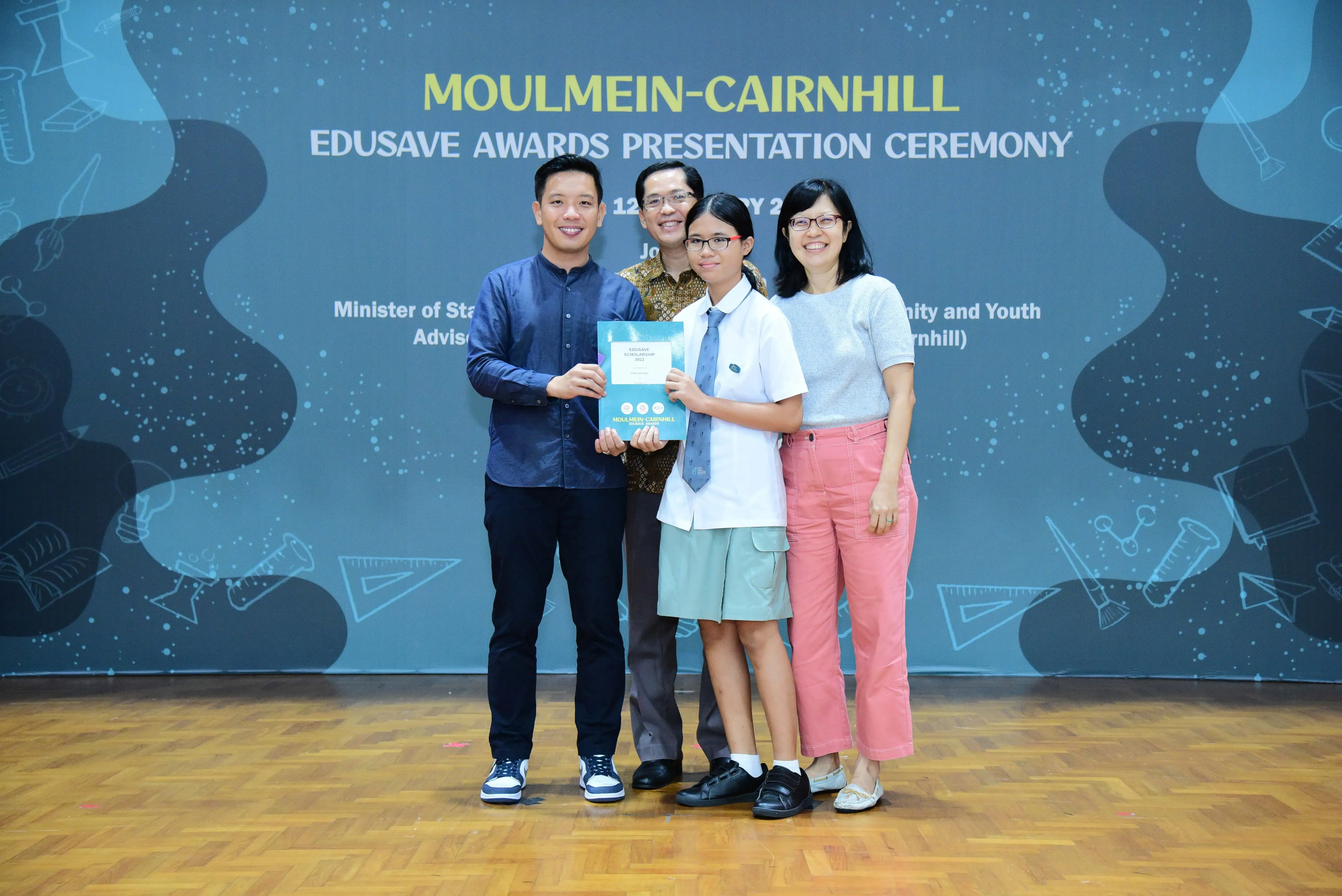Four people pose with an award certificate at the Moulmein-Cairnhill Edusave Awards Presentation Ceremony.