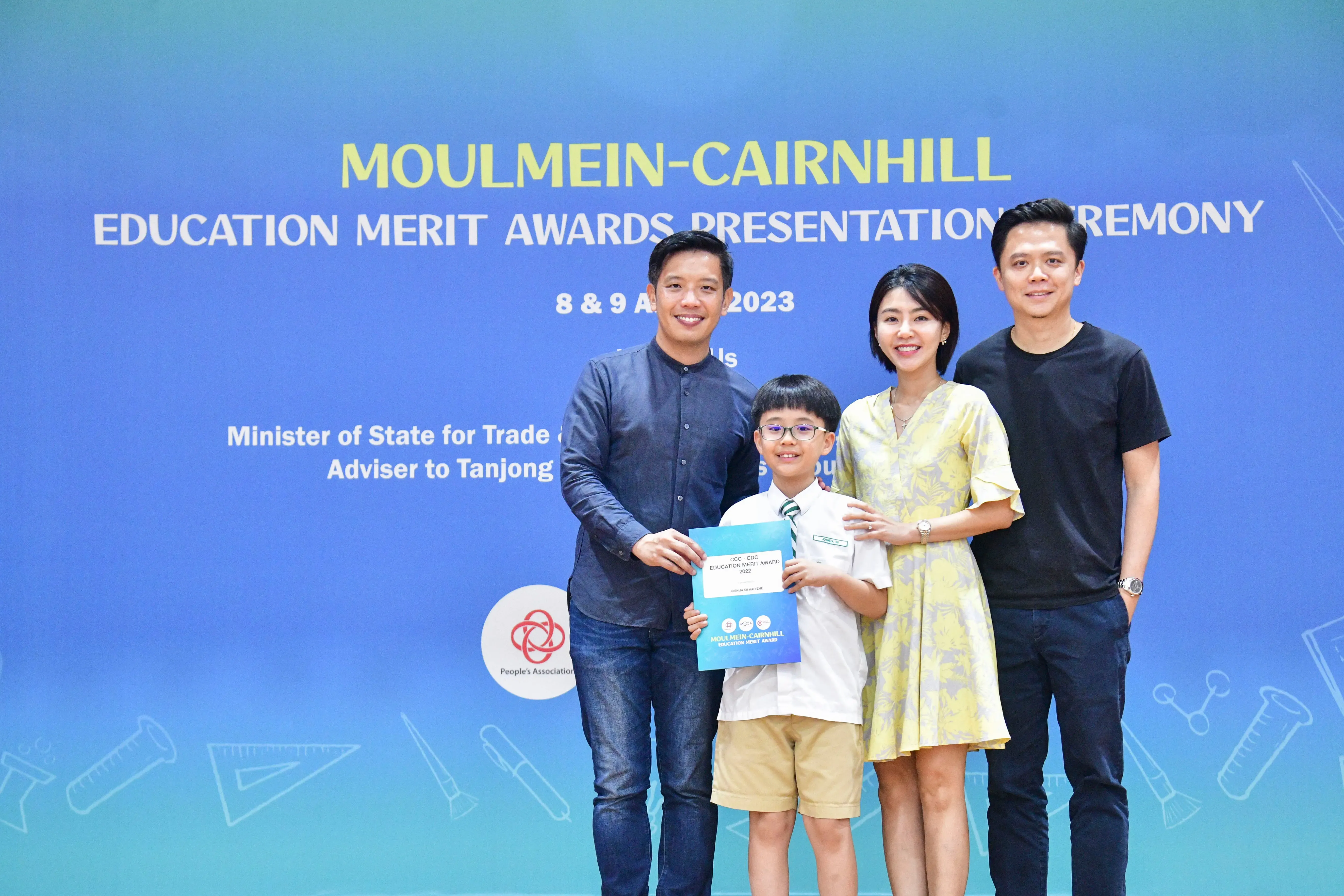 Three adults and a young boy holding a certificate pose at the Moulmein-Cairnhill Education Merit Awards 2023.