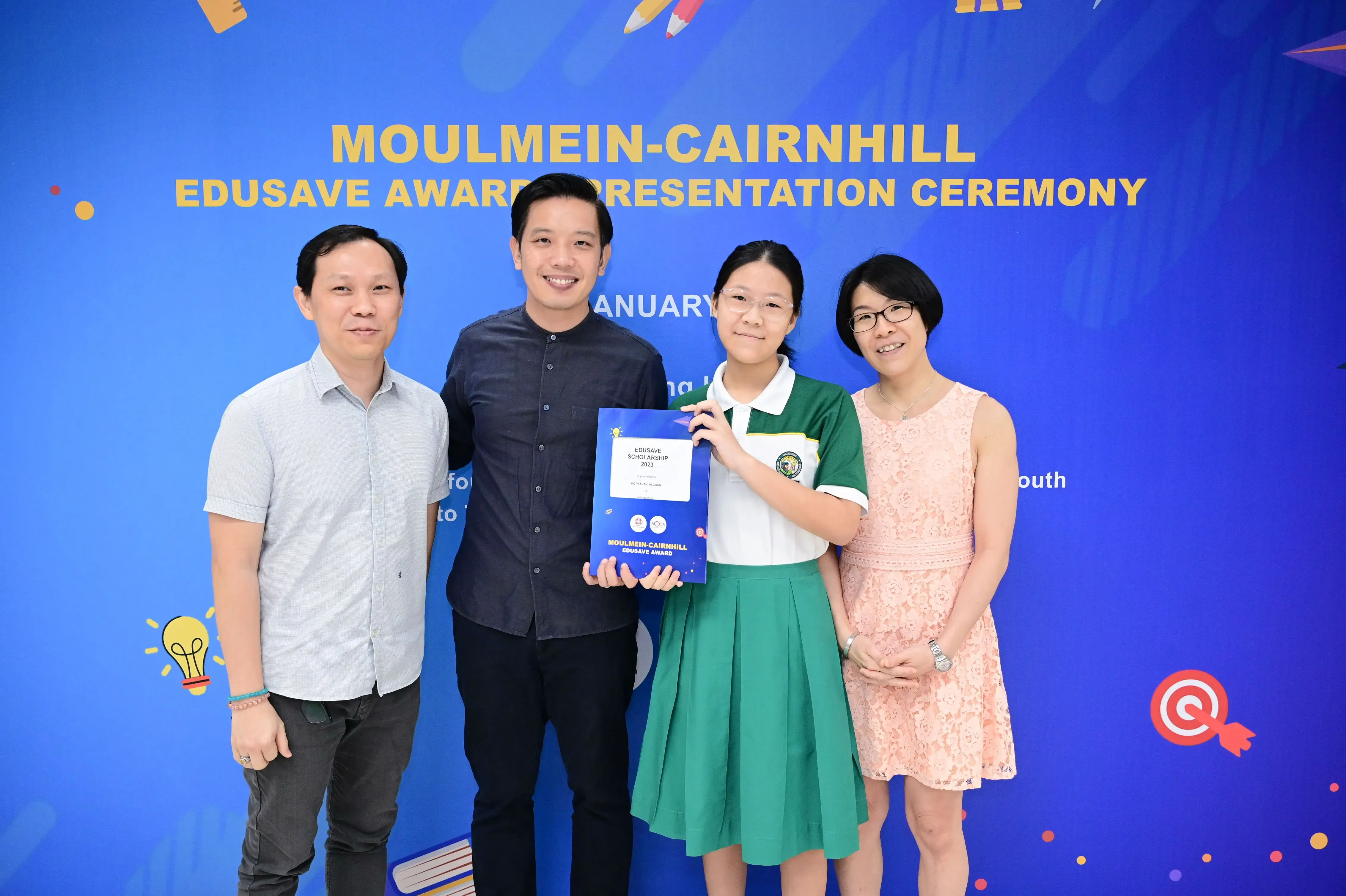 Four people pose at the Moulmein-Cairnhill Edusave Award Presentation Ceremony, with a student holding an award certificate.