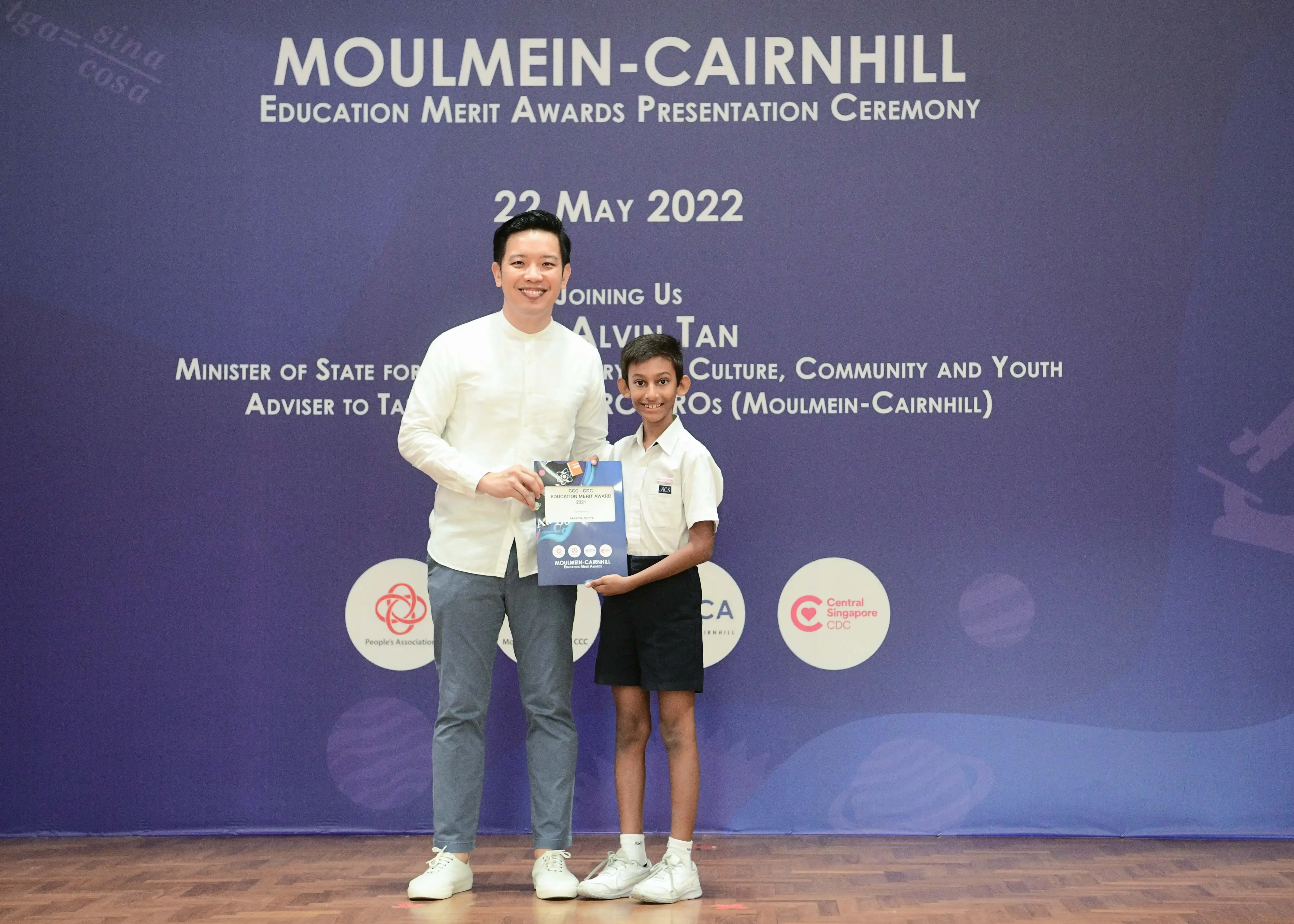 An adult and a young student pose holding an award at the Moulmein-Cairnhill Education Merit Awards Ceremony on 22 May 2022.