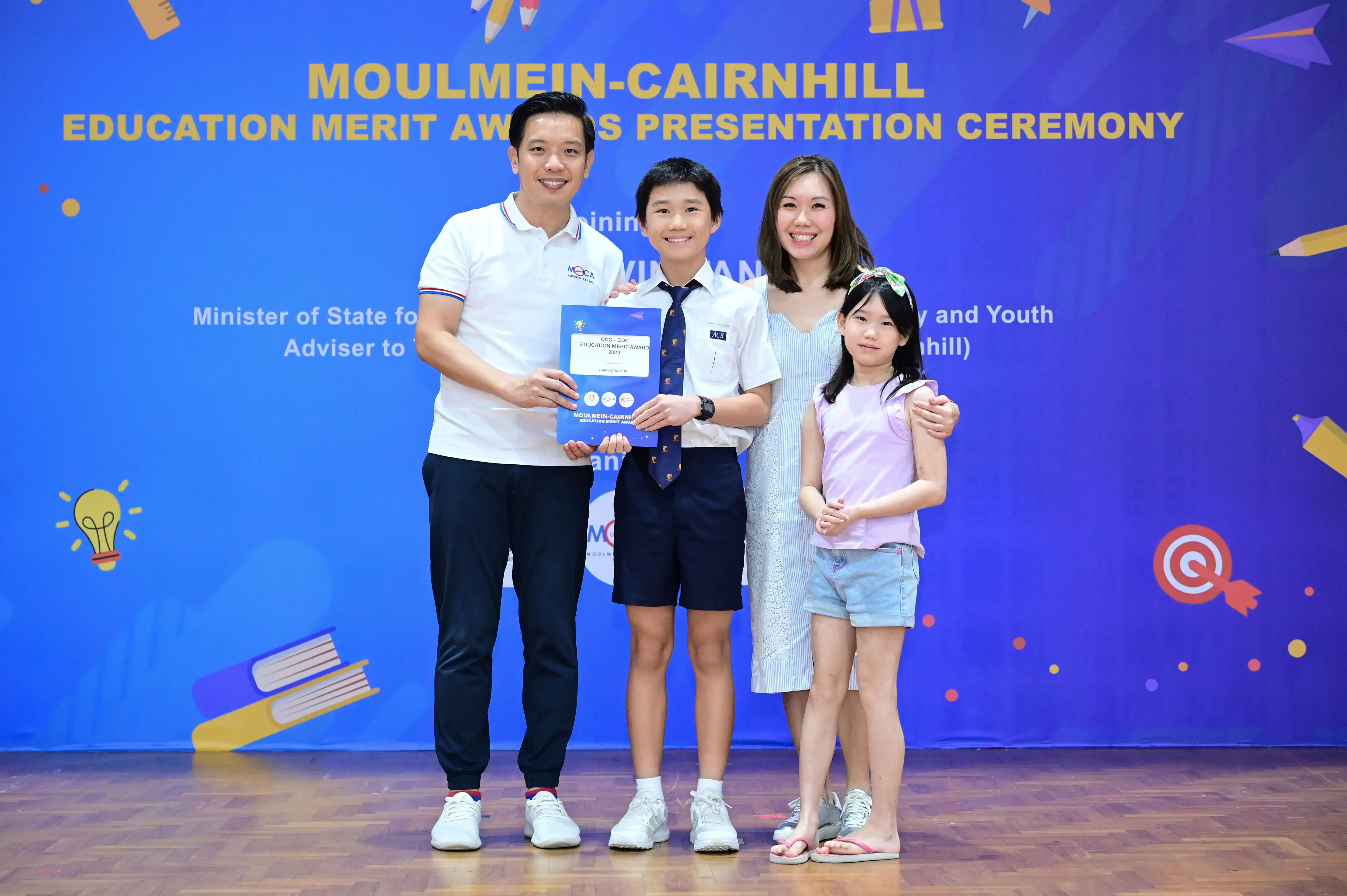 Family of four poses with an award certificate at the Moulmein-Cairnhill Education Merit Awards Presentation Ceremony.