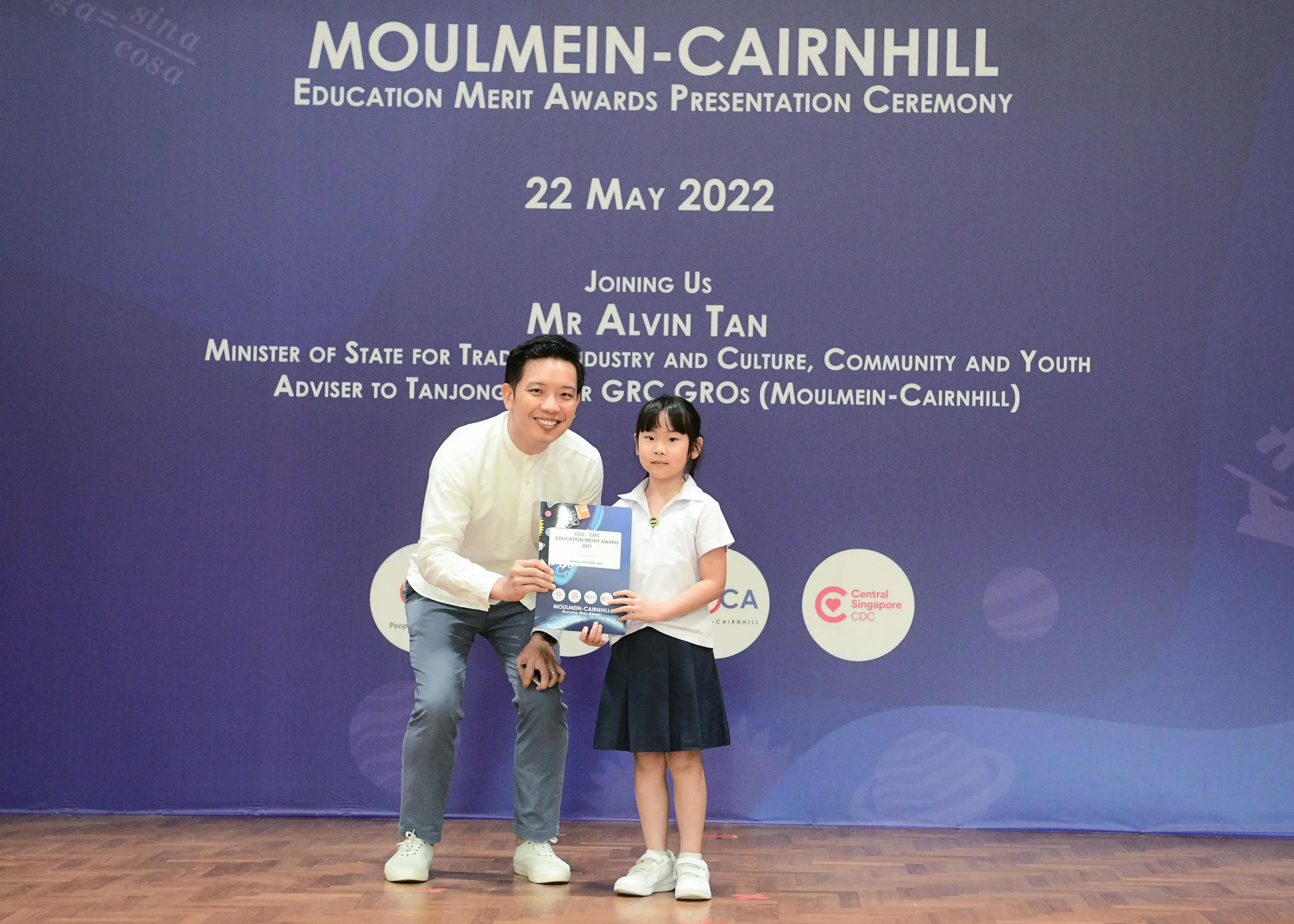 A man and a young girl hold a certificate together at the Moulmein-Cairnhill Education Merit Awards on 22 May 2022.