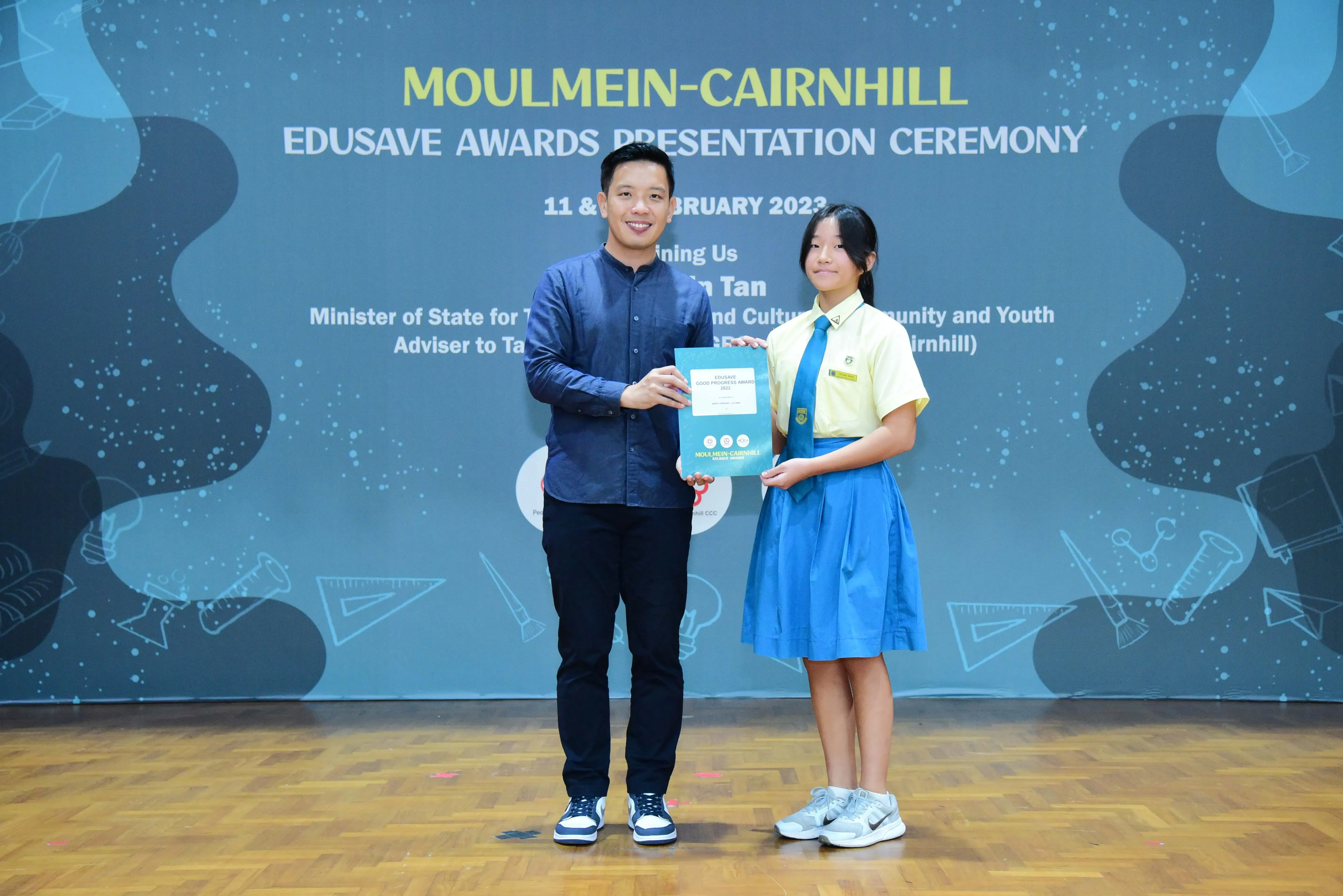 A man and a uniformed schoolgirl hold an award together at the Moulmein-Cairnhill Edusave Awards Ceremony 2023.