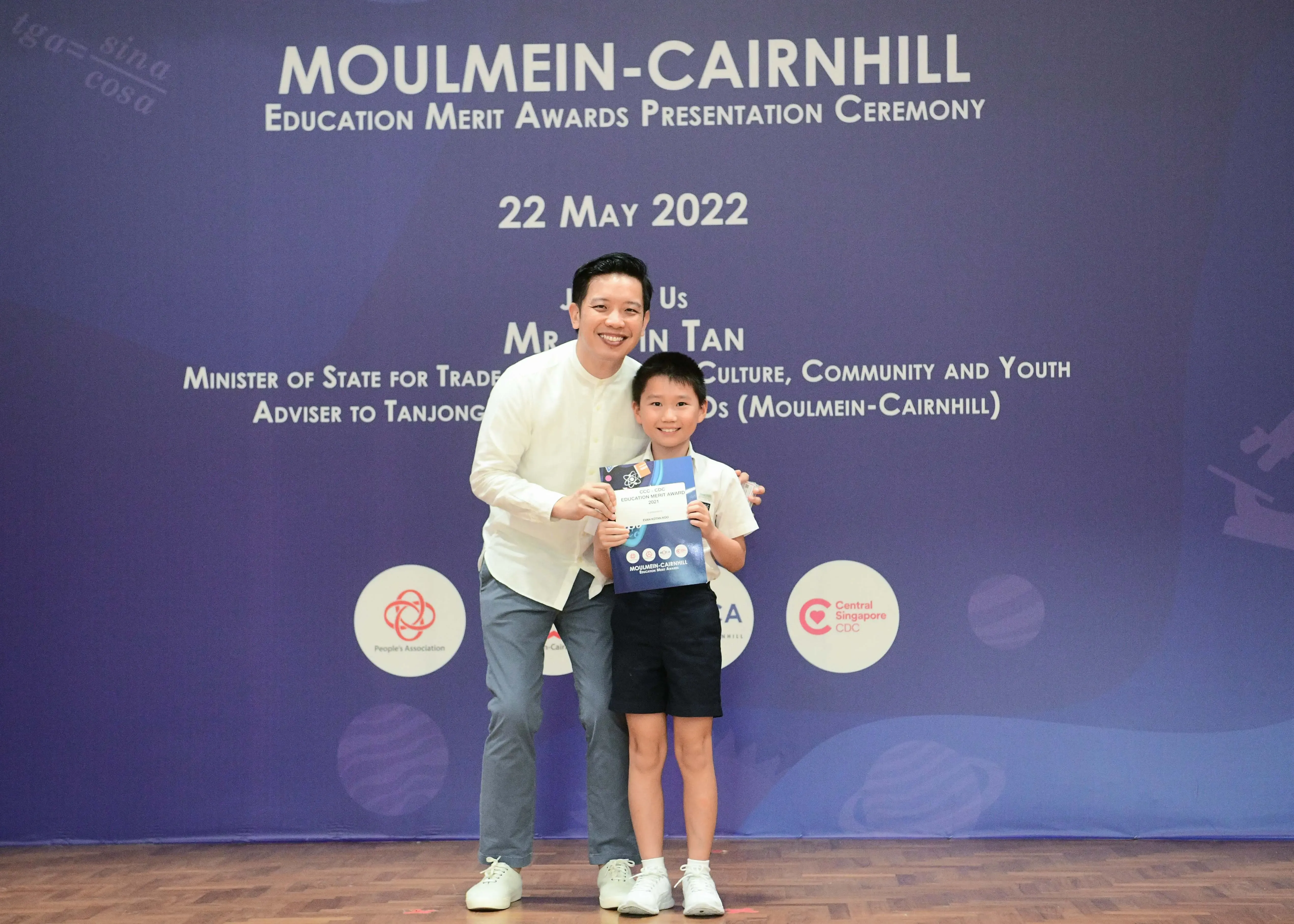 A man and a young boy pose together holding an award certificate at the Moulmein-Cairnhill Education Merit Awards on 22 May 2022.
