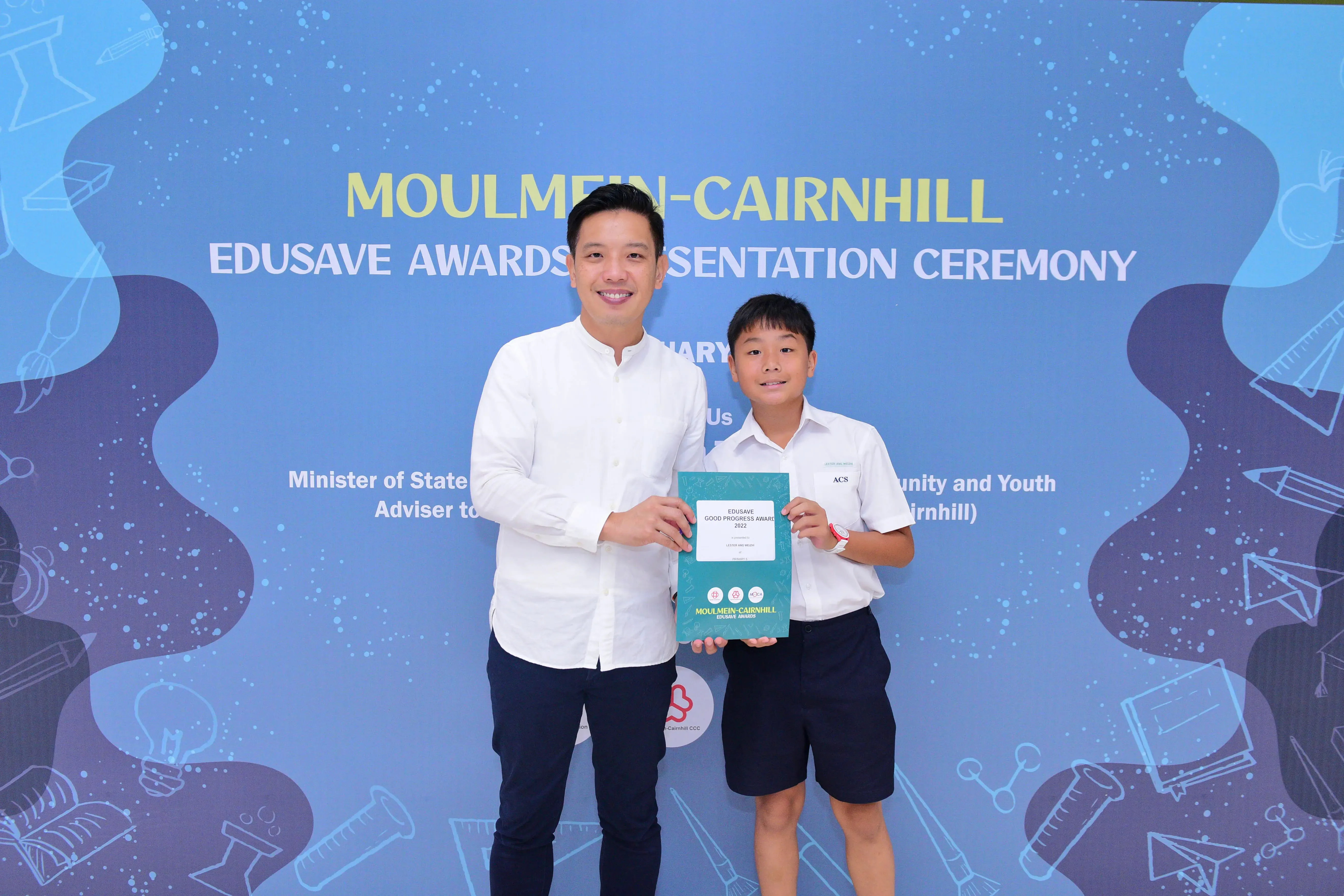 Man and young boy hold an Edusave Good Progress Award certificate at the Moulmein-Cairnhill Edusave Awards Ceremony.