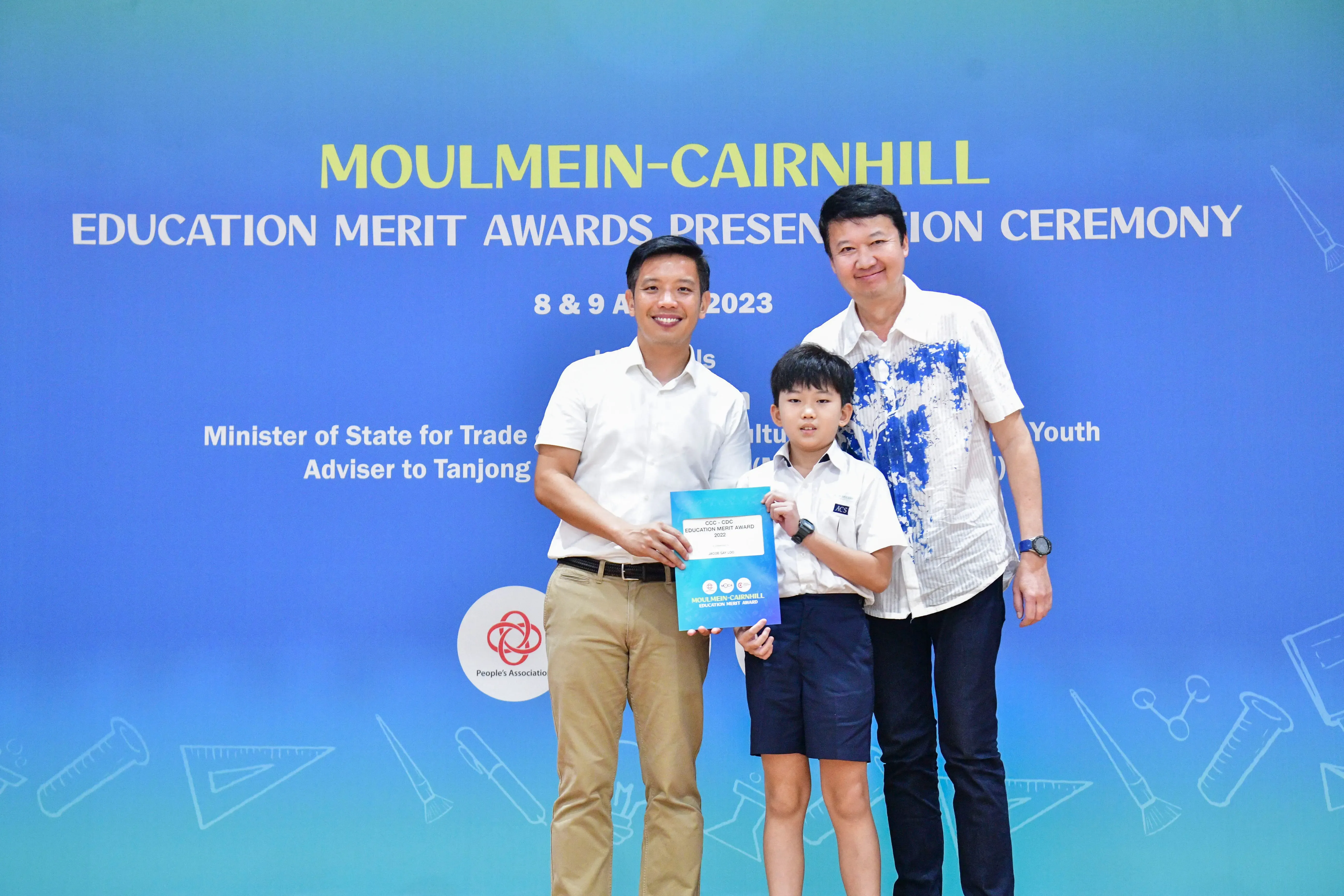 Two men and a young boy pose holding a certificate at the Moulmein-Cairnhill Education Merit Awards 2023.