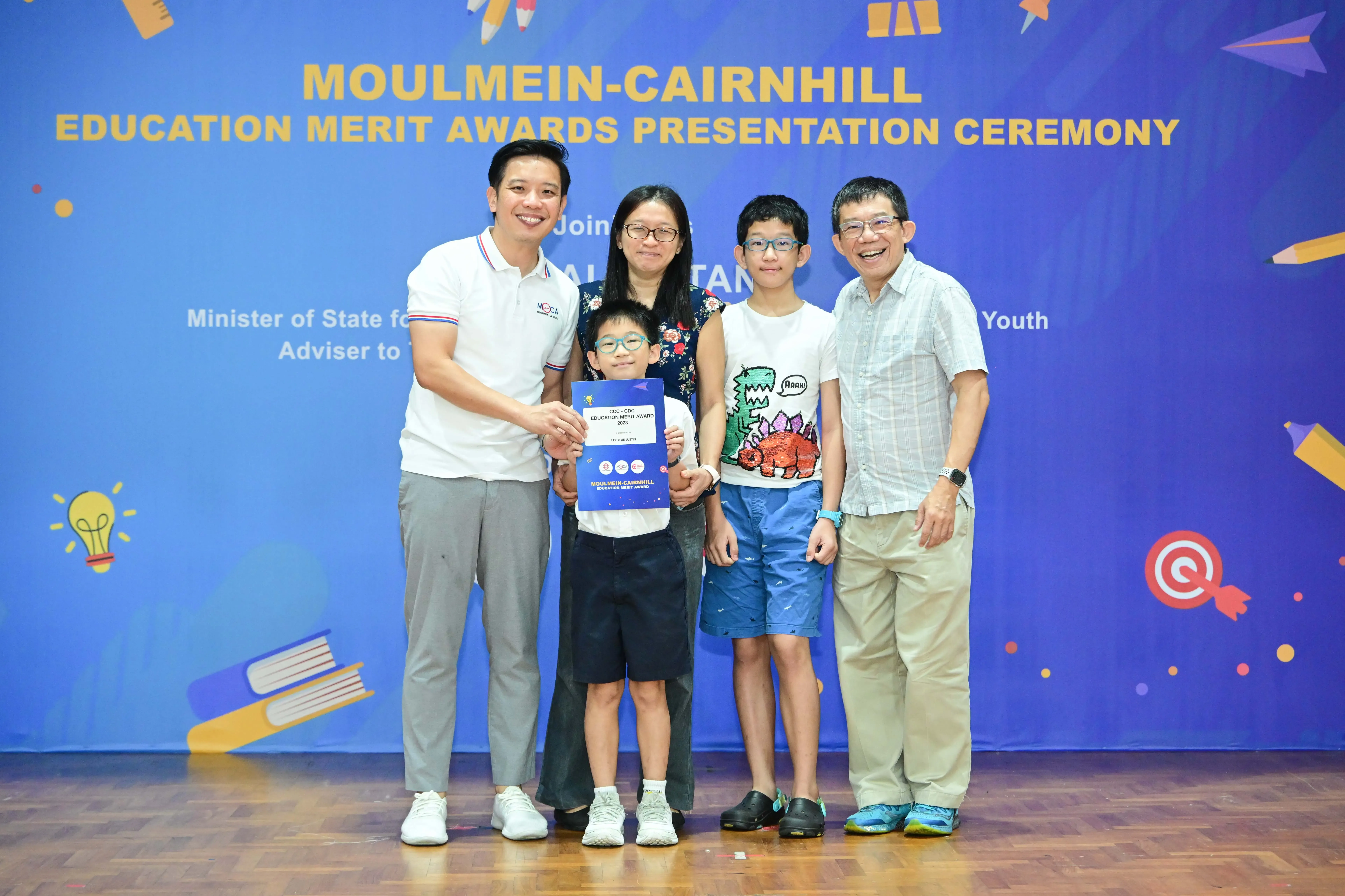 Five people pose with a certificate at the Moulmein-Cairnhill Education Merit Awards Presentation Ceremony.