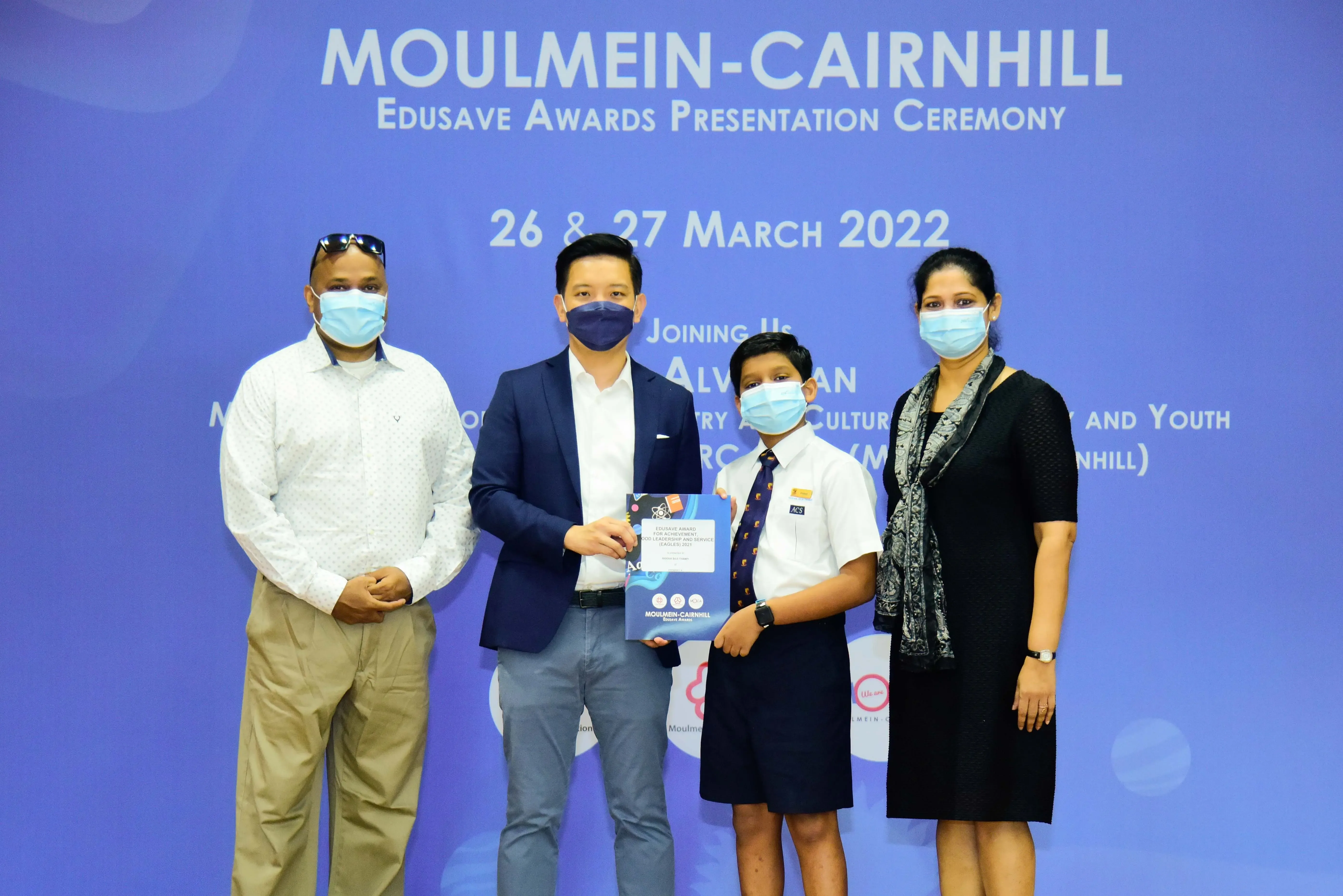 Four masked people pose at the Moulmein-Cairnhill Edusave Awards Presentation Ceremony on 26-27 March 2022.