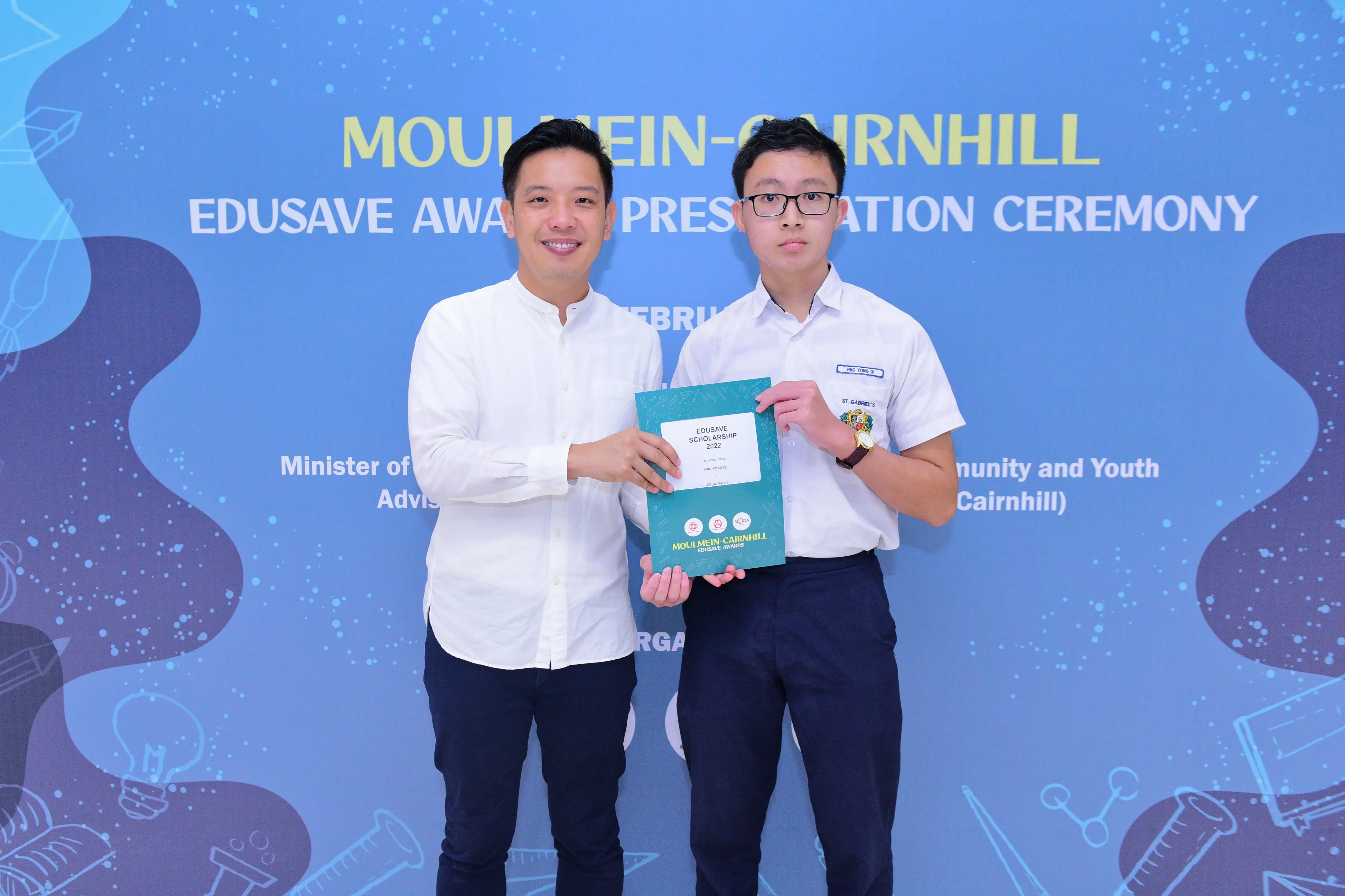 Two men hold an Edusave Scholarship certificate at the Moulmein-Cairnhill Edusave Awards Presentation Ceremony.