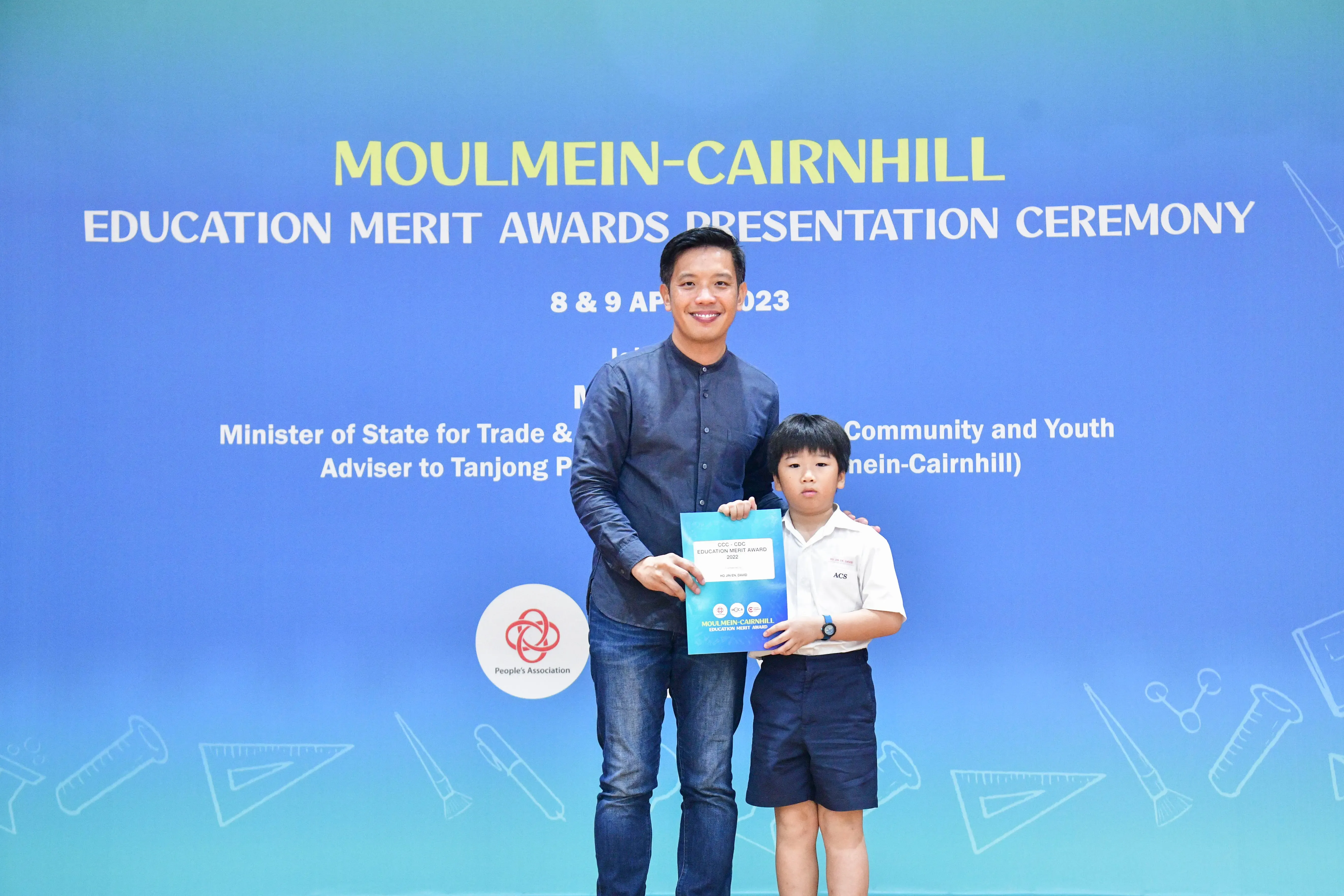 A man and a young boy in school uniform pose holding an award certificate at the Moulmein-Cairnhill Education Merit Awards 2023.