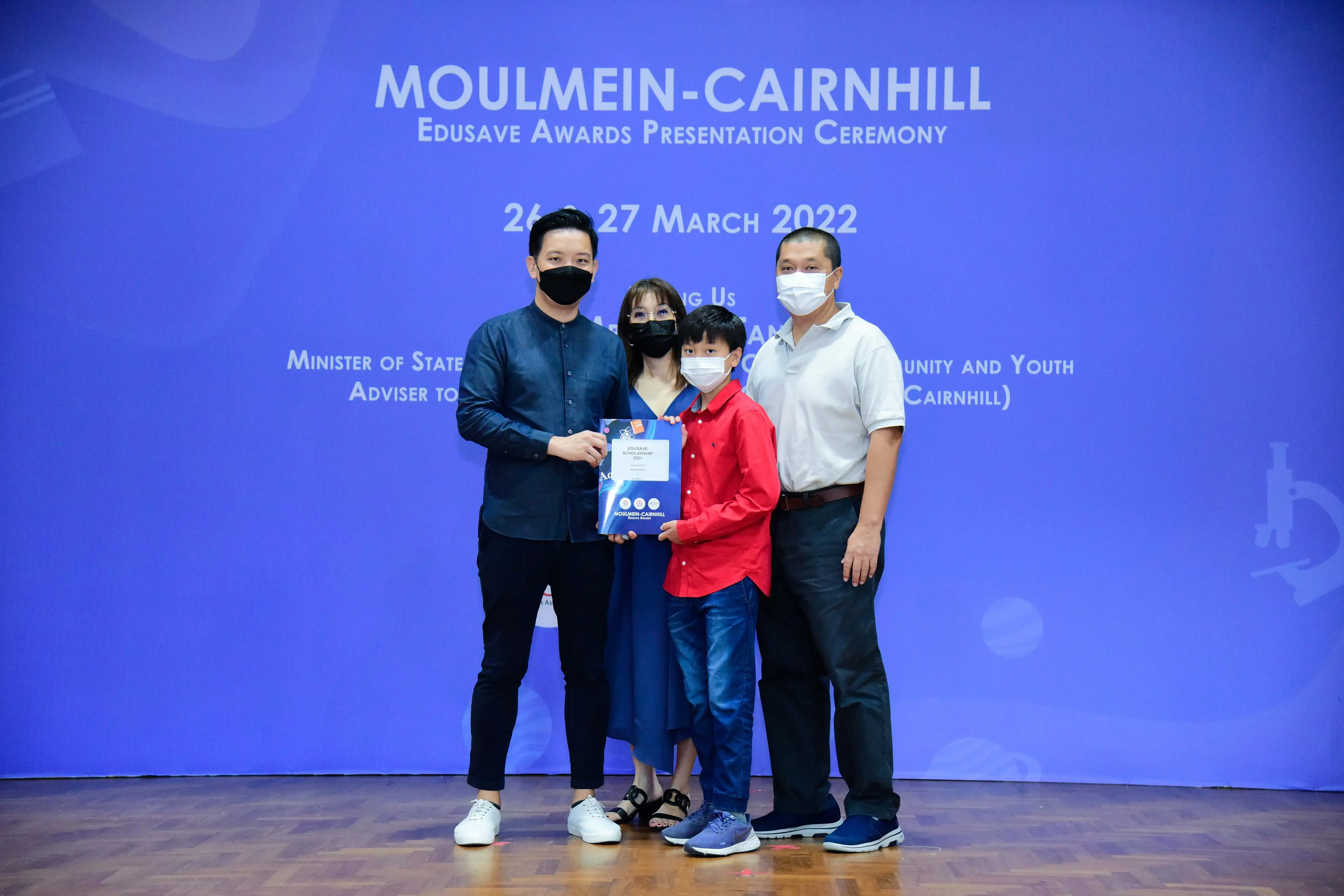 Four masked people pose with a certificate at the Moulmein-Cairnhill Edusave Awards Presentation Ceremony, March 2022.