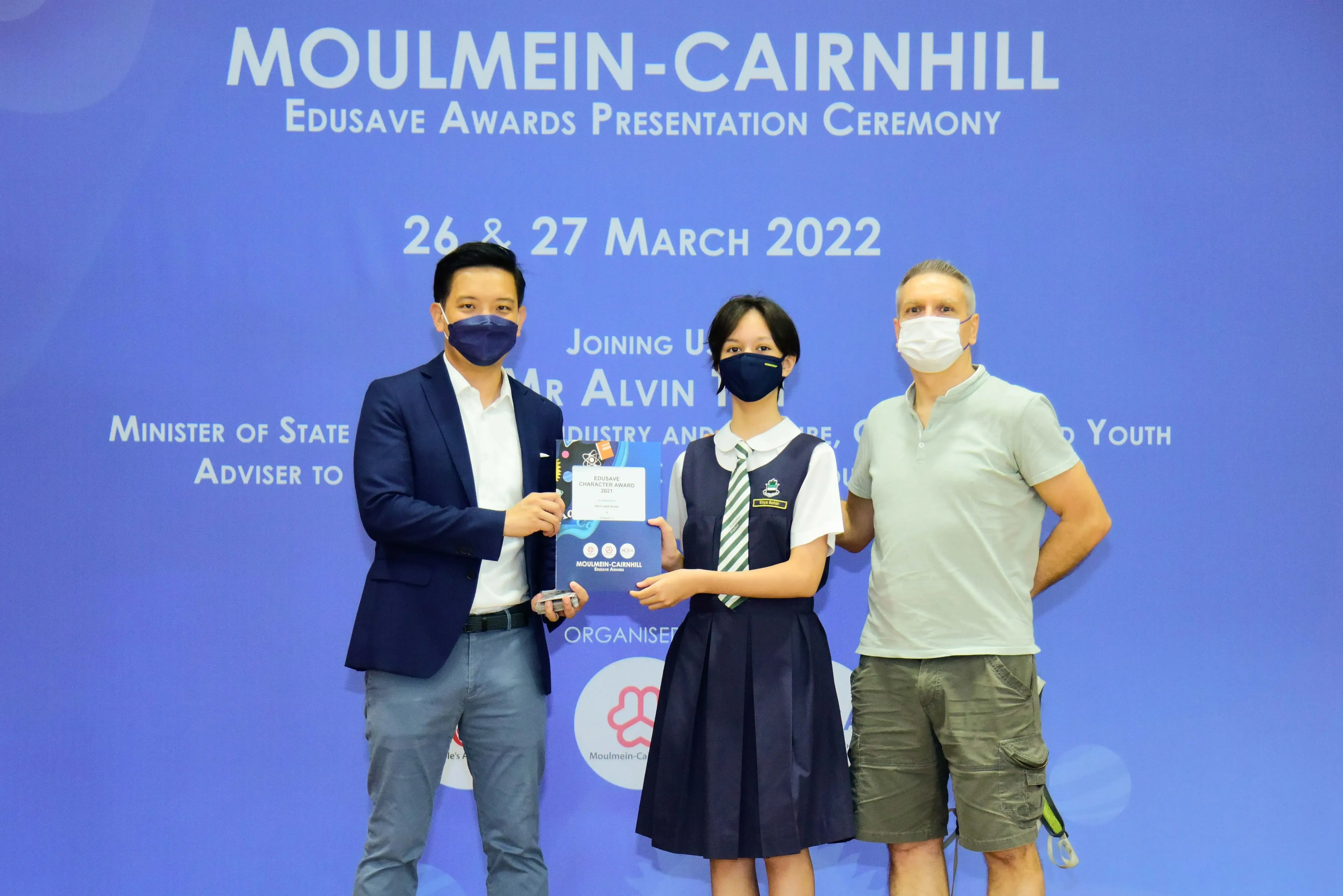 Three masked people pose at the Moulmein-Cairnhill Edusave Awards Presentation Ceremony on 26-27 March 2022.