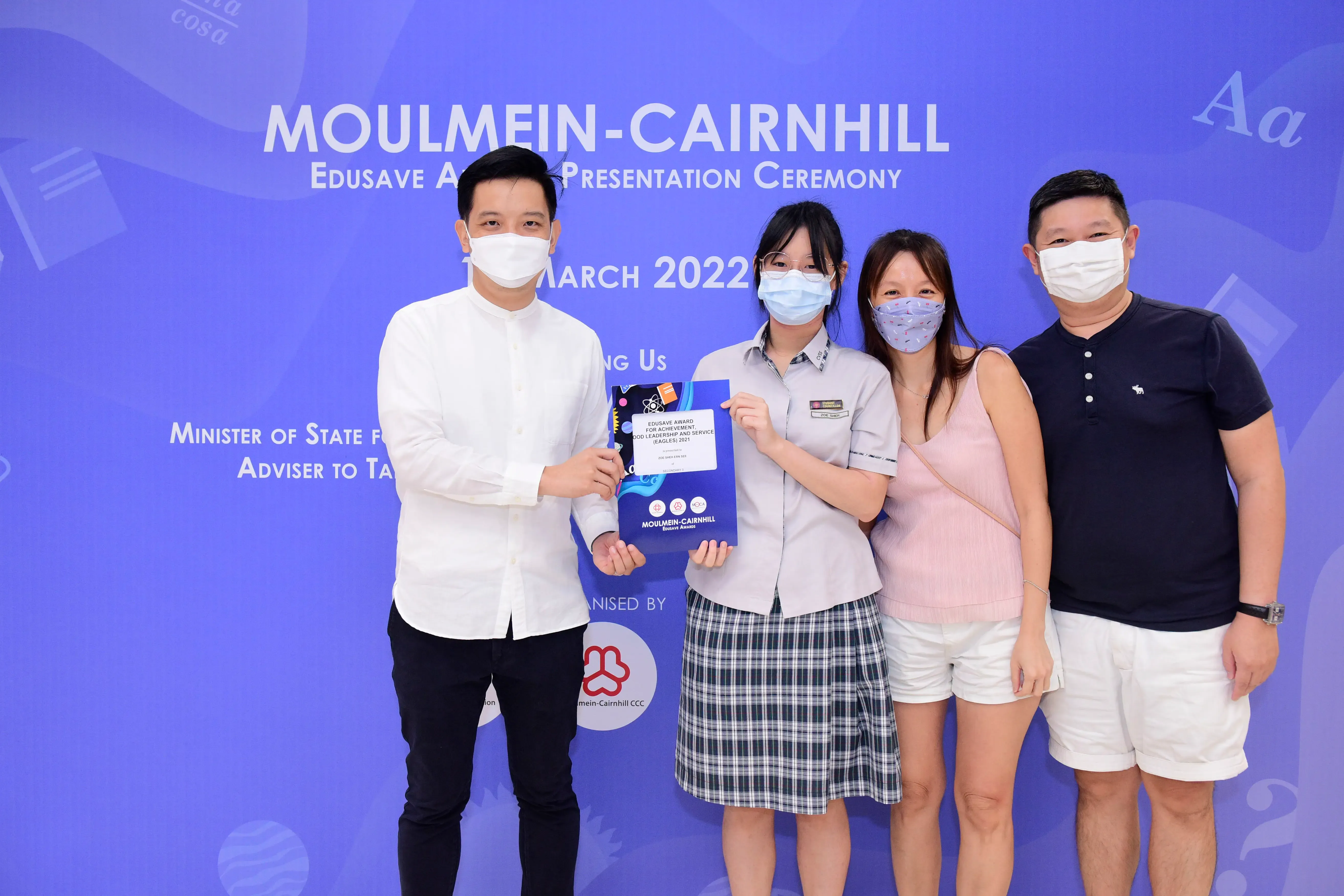 Four masked people pose at the Moulmein-Cairnhill Edusave Award Presentation Ceremony in March 2022.