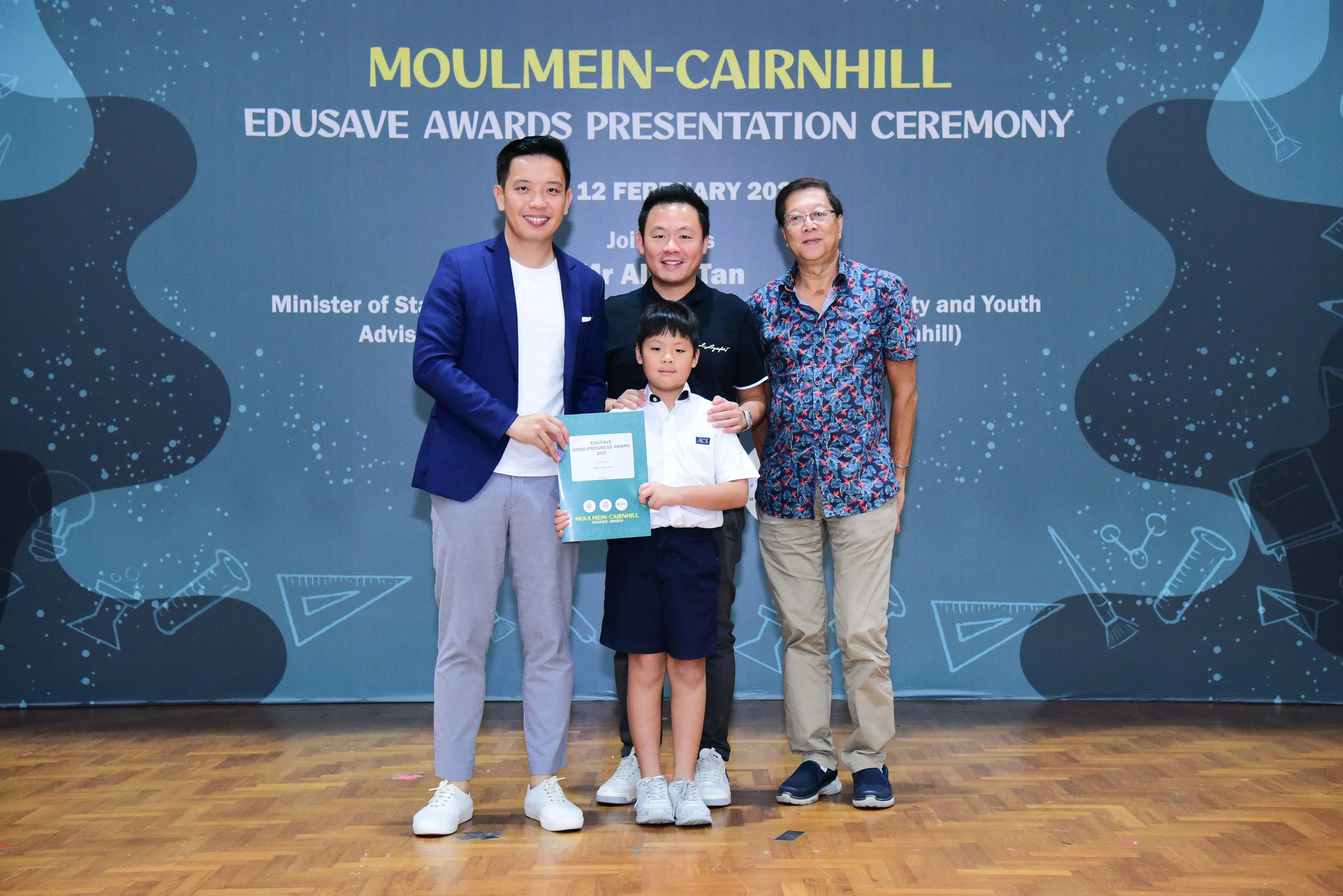Three adults and a young boy holding a certificate pose at the Moulmein-Cairnhill Edusave Awards Presentation Ceremony.