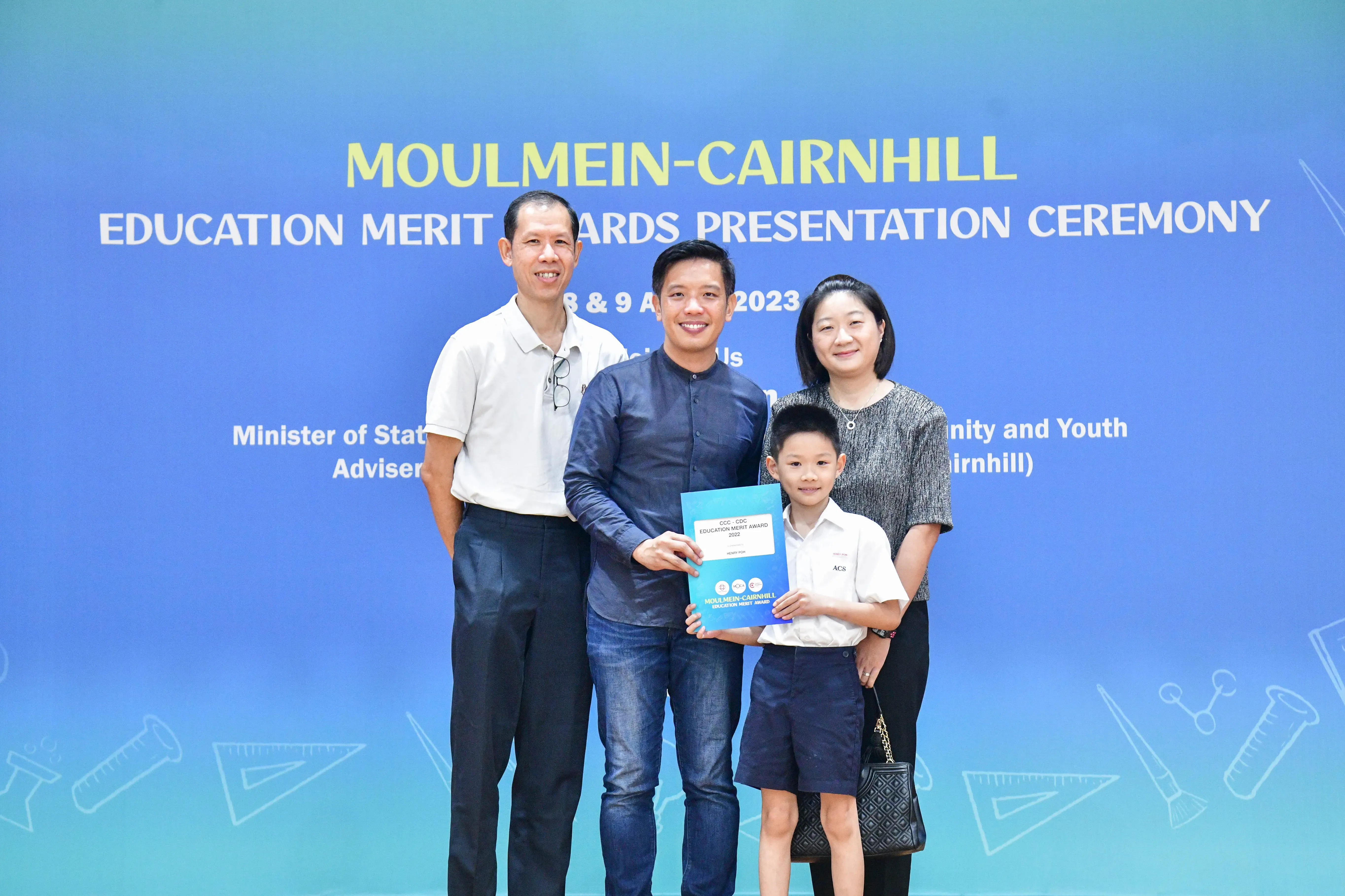 Three adults and a young boy pose holding a certificate at the Moulmein-Cairnhill Education Merit Awards 2023.