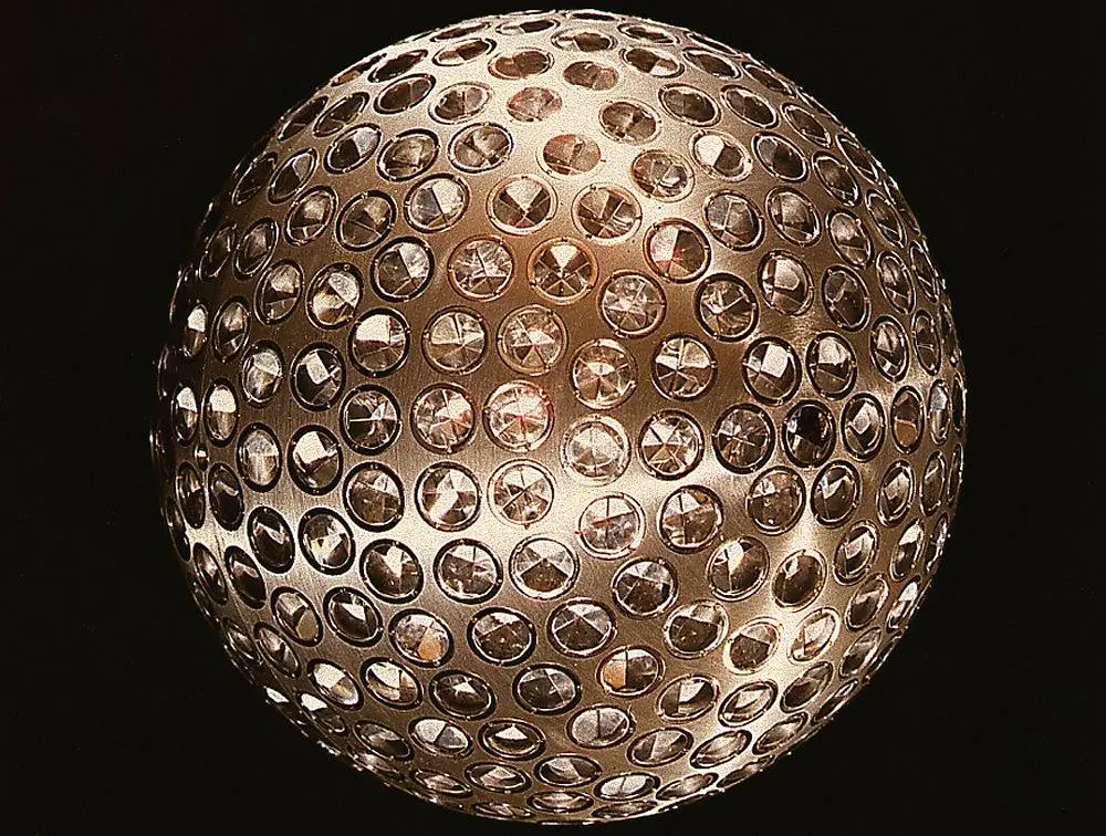 A metallic sphere covered in small circular crystal or gem inlays, set against a black background.