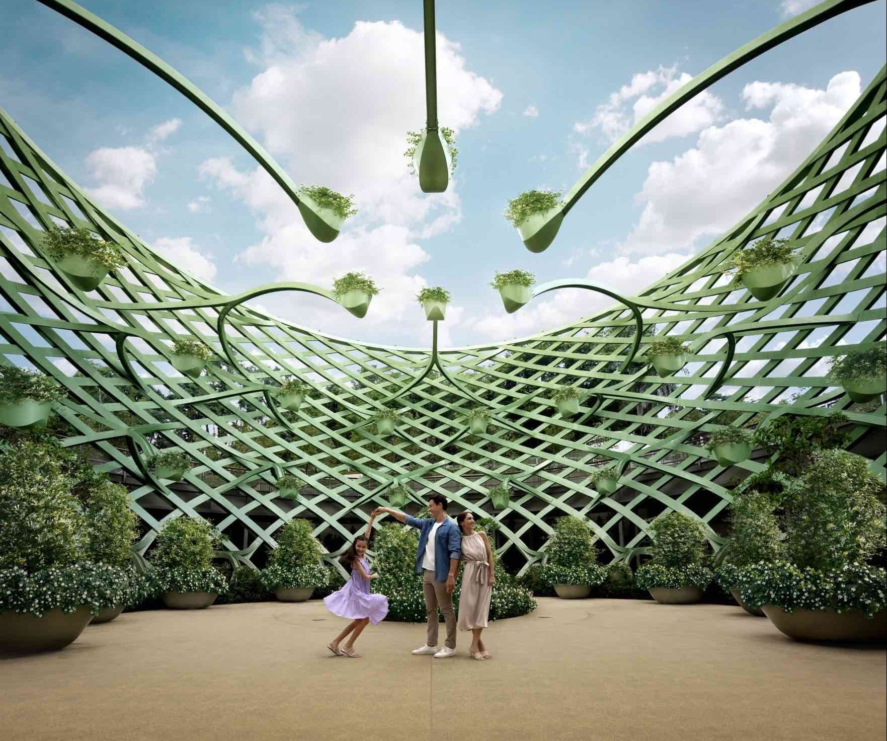 A family of three dances under a green lattice pergola with hanging planters and large potted shrubs.
