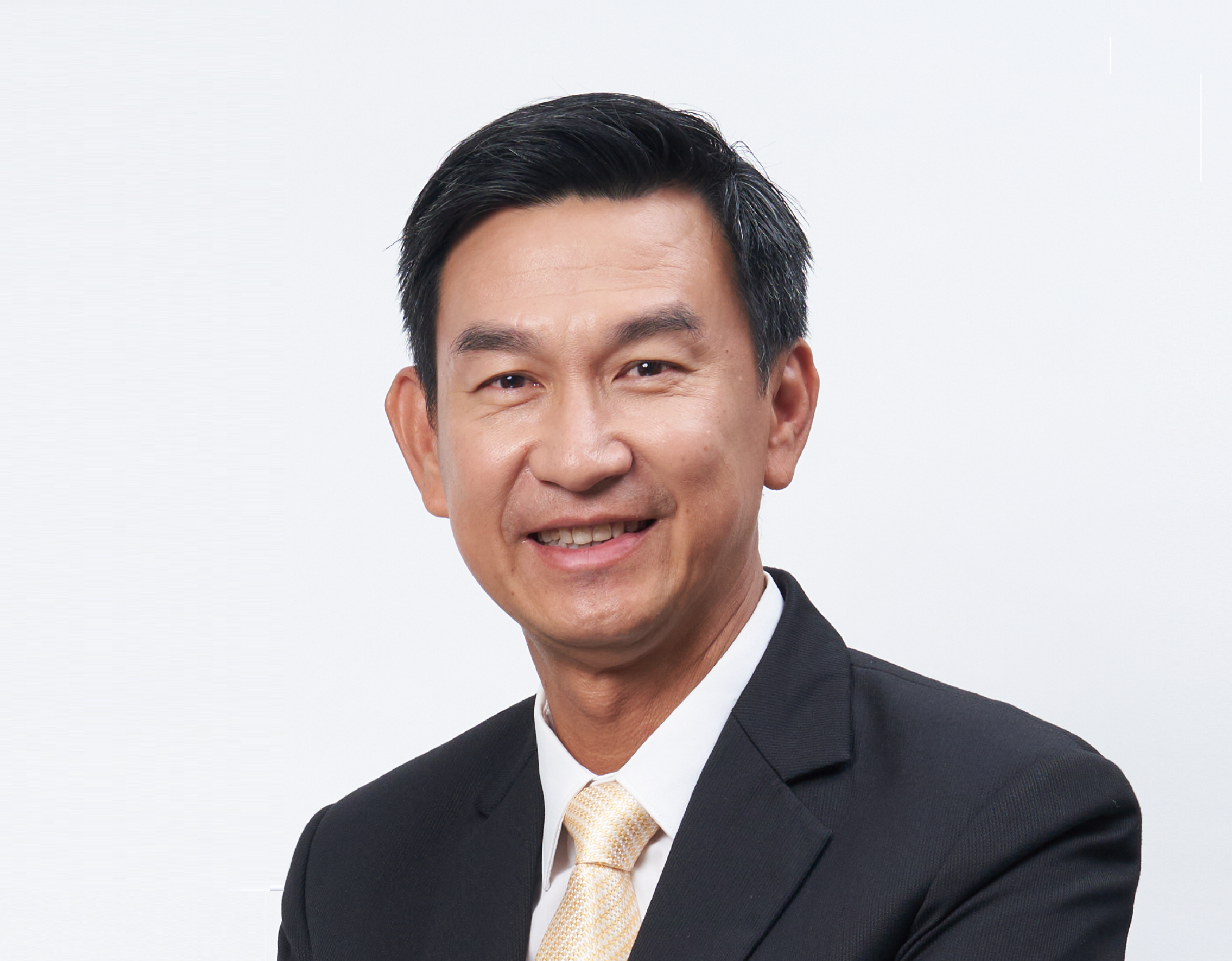 Middle aged man in shirt, jacket and yellow tie against a grey background