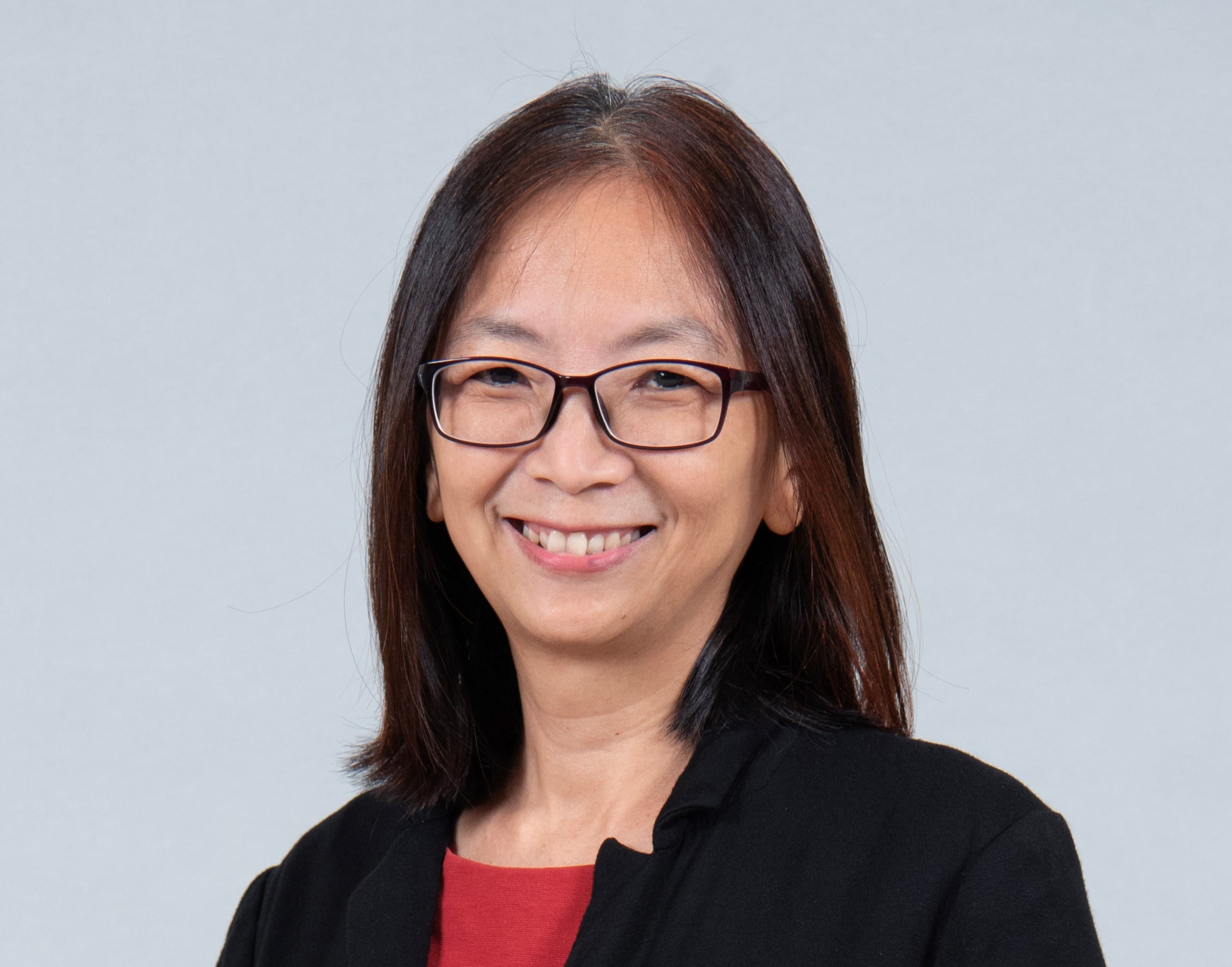 A smiling lady with shoulder length with a black jacket over a red top