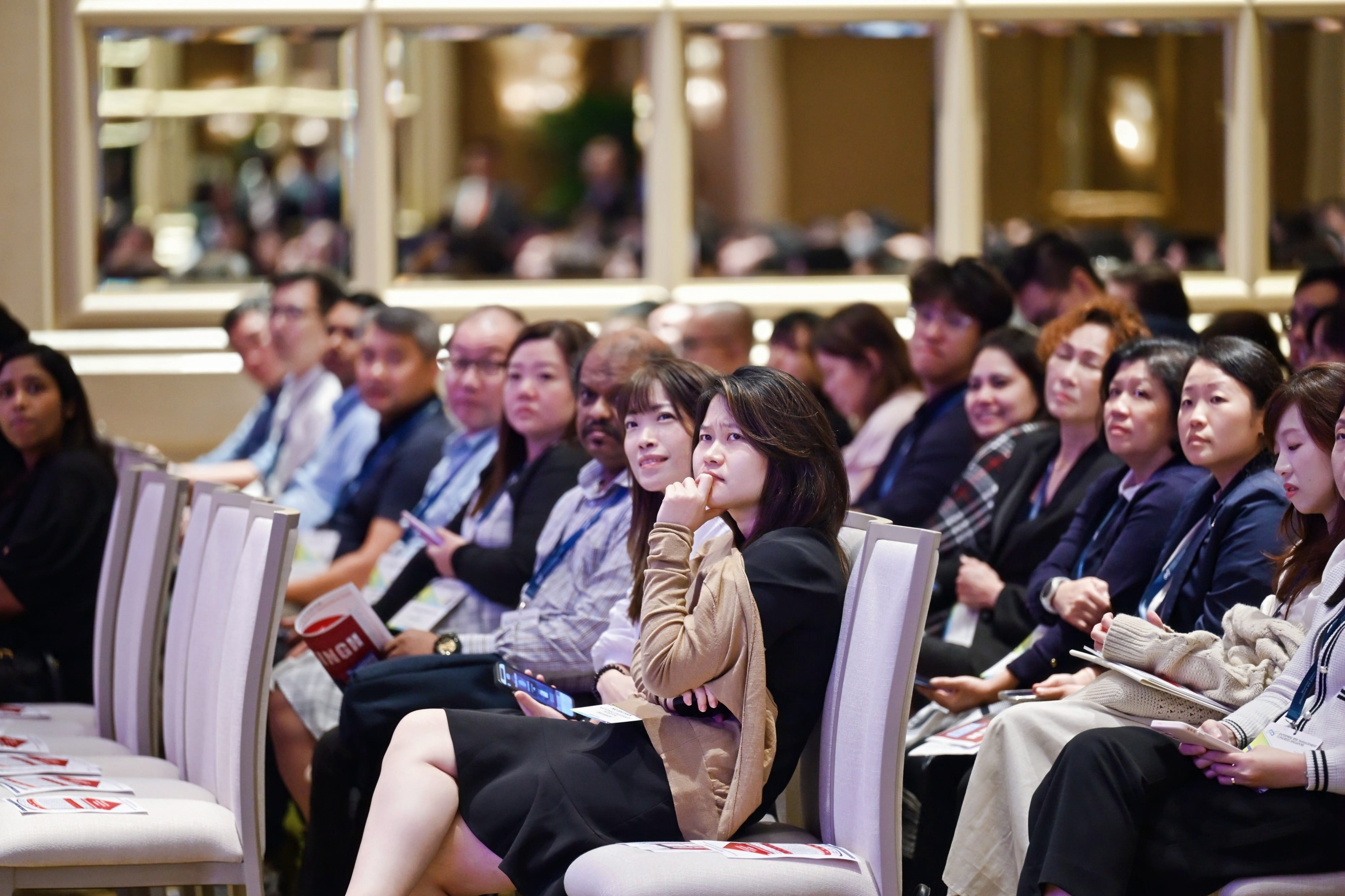 Delegates sitting on chairs, listening attentively to the conference.