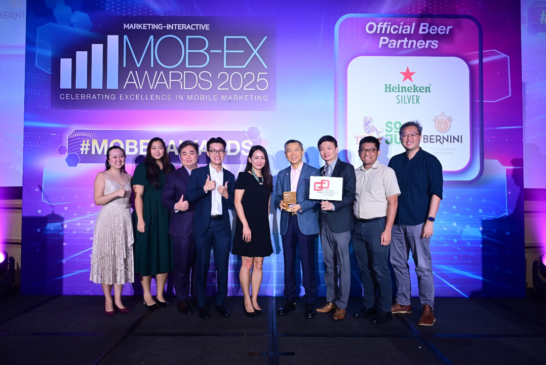 Eight people pose on stage at the MOB-EX Awards 2025 event, with one holding a trophy.