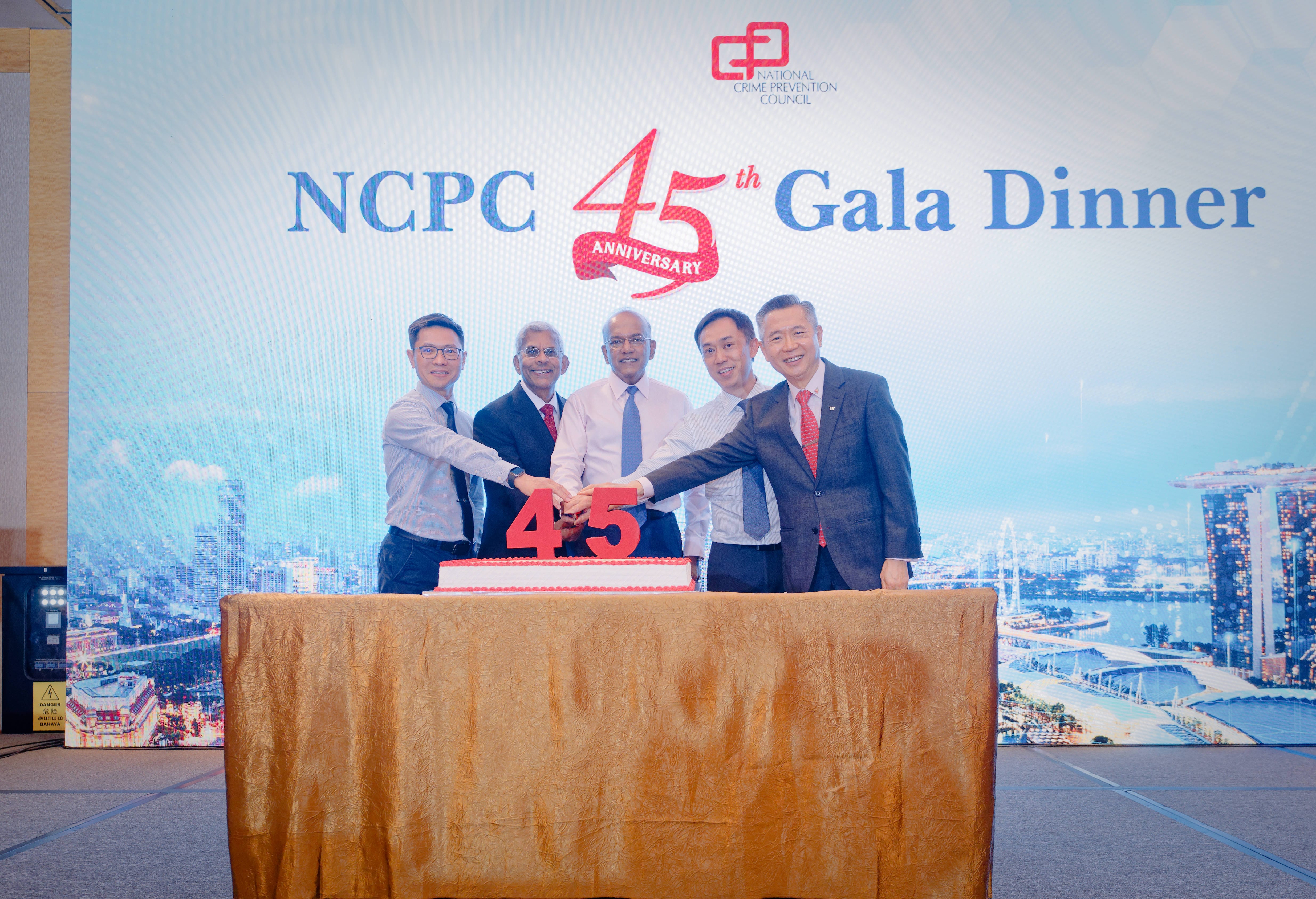 Five men in formal attire stand behind a celebratory cake shaped like the numbers "45", holding a knife together for a ceremonial cake-cutting in front of a backdrop reading "NCPC 45th Gala Dinner".