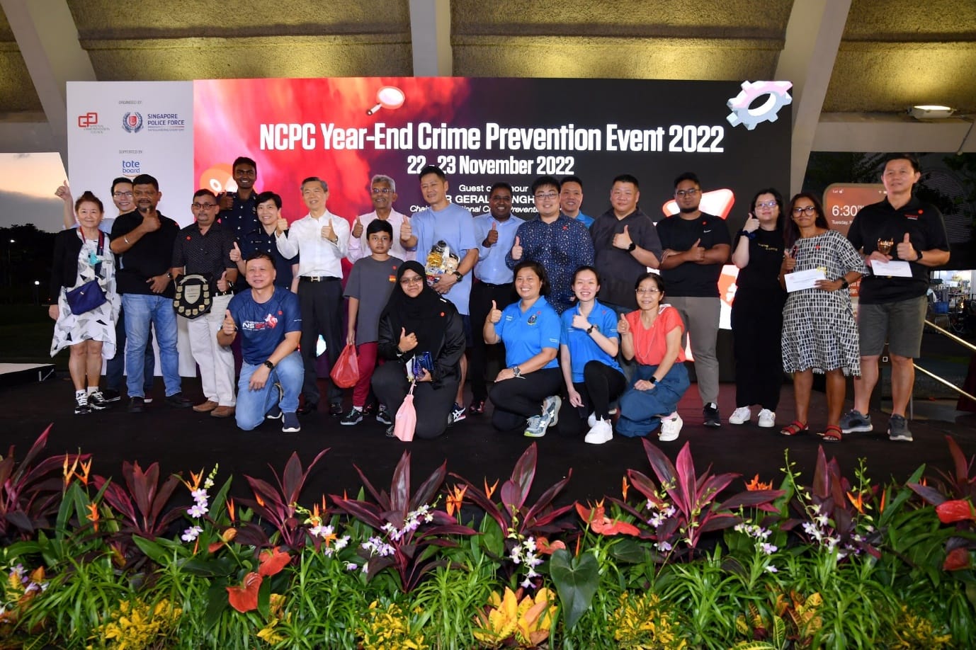 Group of people posing with thumbs up in front of NCPC Year-End Crime Prevention Event 2022 banner.