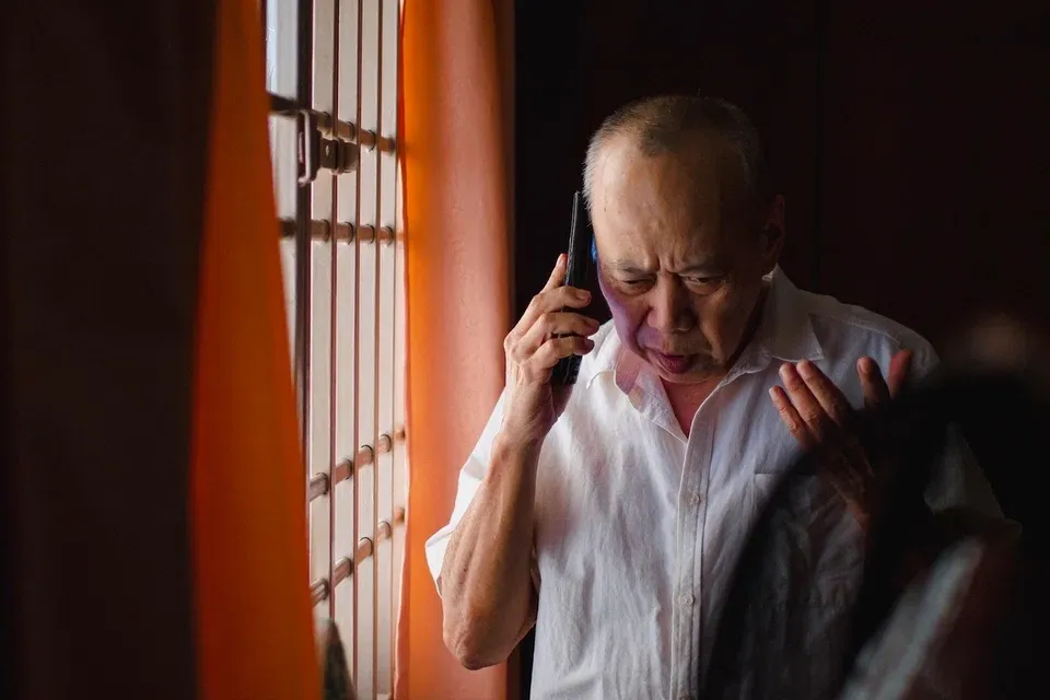 Elderly man looking distressed while speaking on a mobile phone.