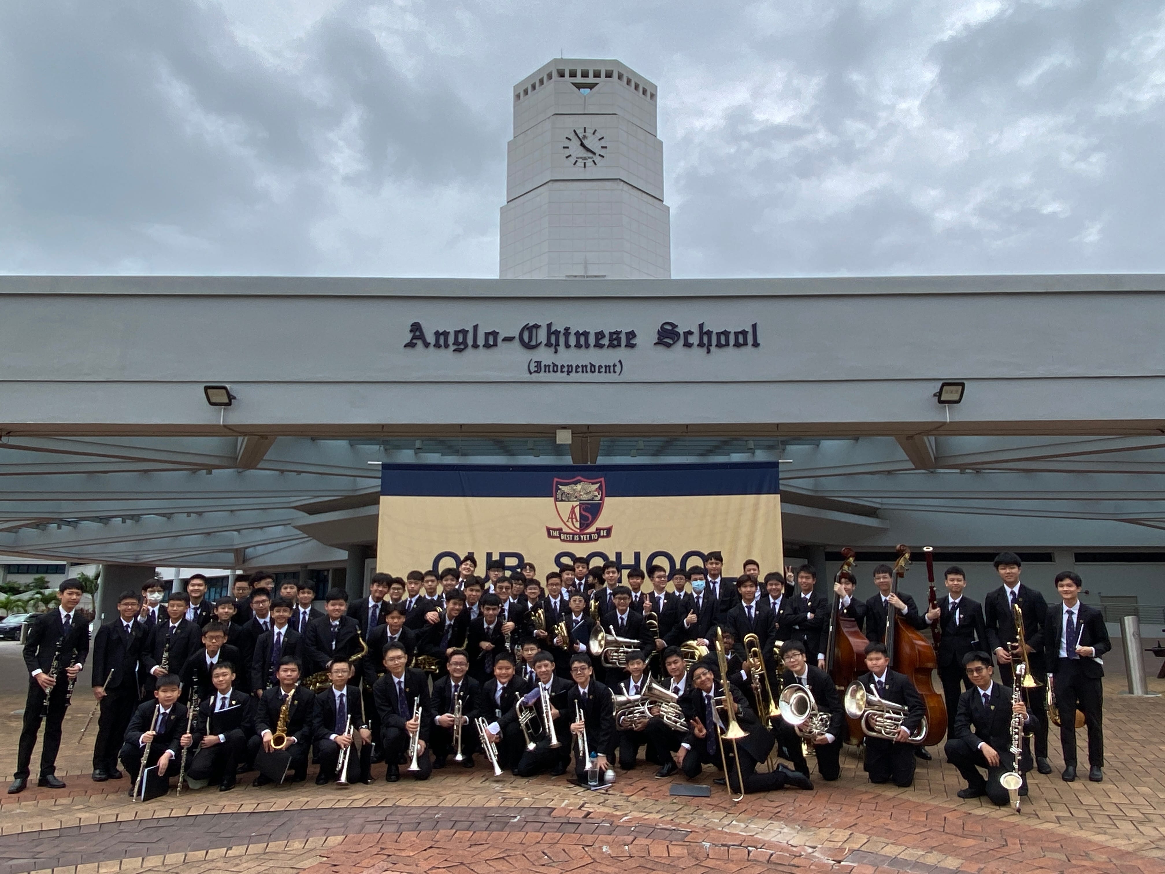 Large group of students in black uniforms holding instruments outside Anglo-Chinese School (Independent).