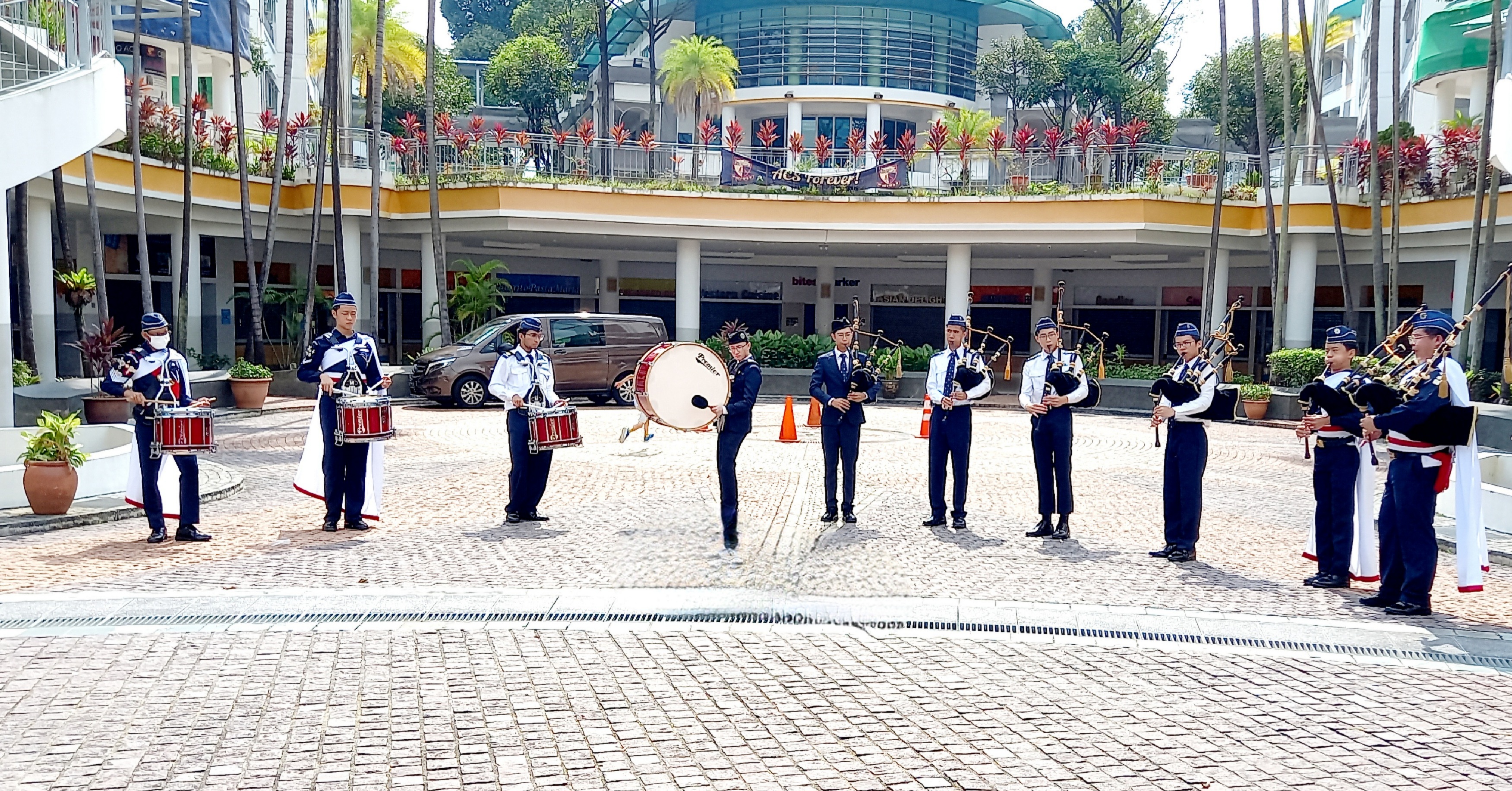 A group of BB band members performing in an outdoor school courtyard