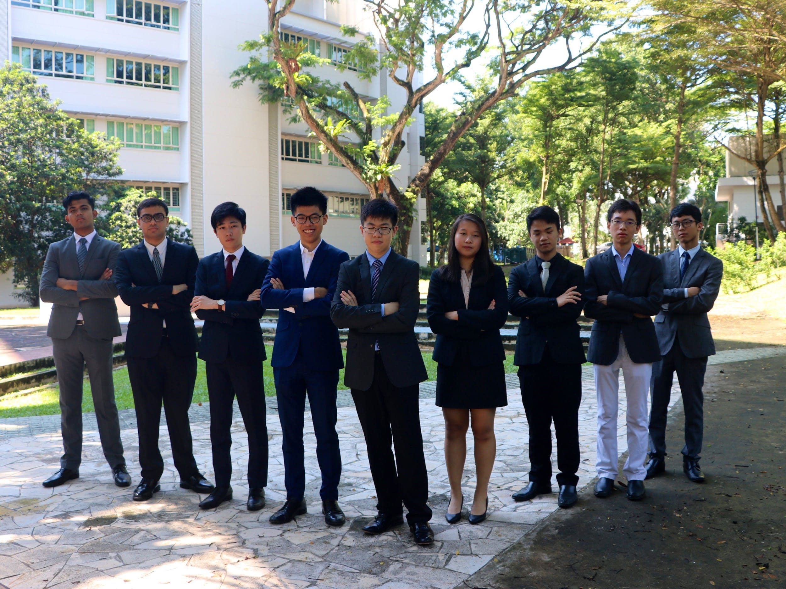 ACS(I) Young Diplomats Society members in formal suits and blazers pose for a group photo outdoors on school grounds before or after a MUN conference.