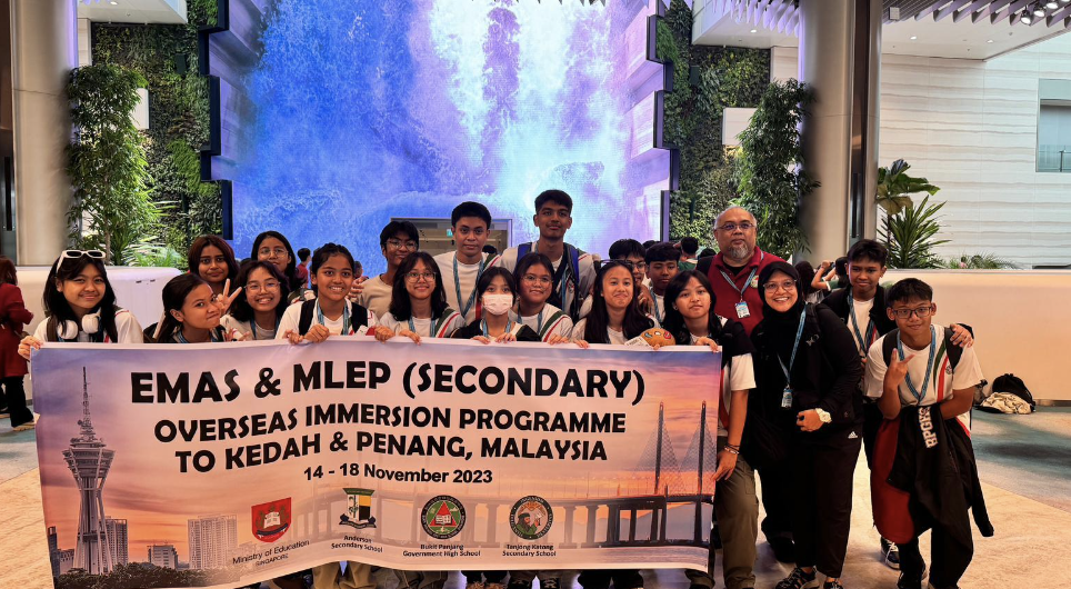 Group of students and a teacher holding a banner for EMAS & MLEP Overseas Immersion Programme to Malaysia, November 2023.