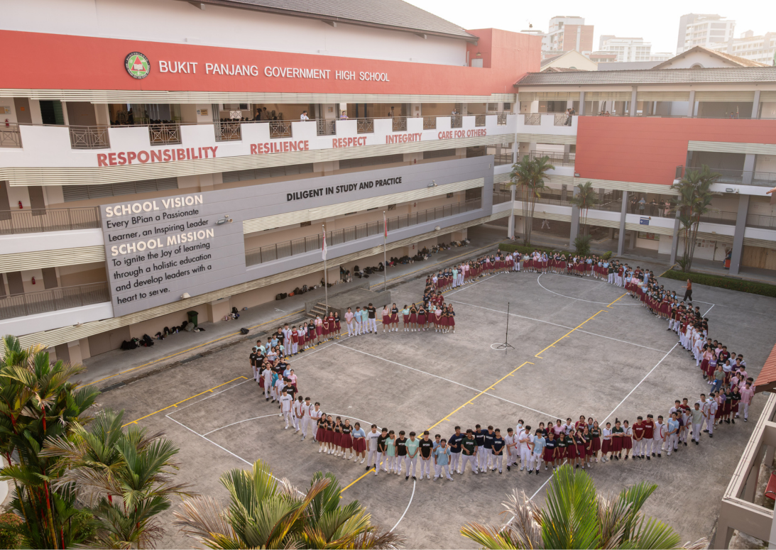 Students in uniforms form a large circle in the courtyard of Bukit Panjang Government High School.