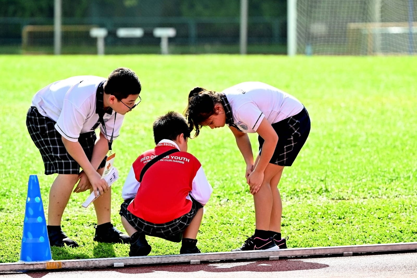 Links checking on casualty's knee injury during Sports Day