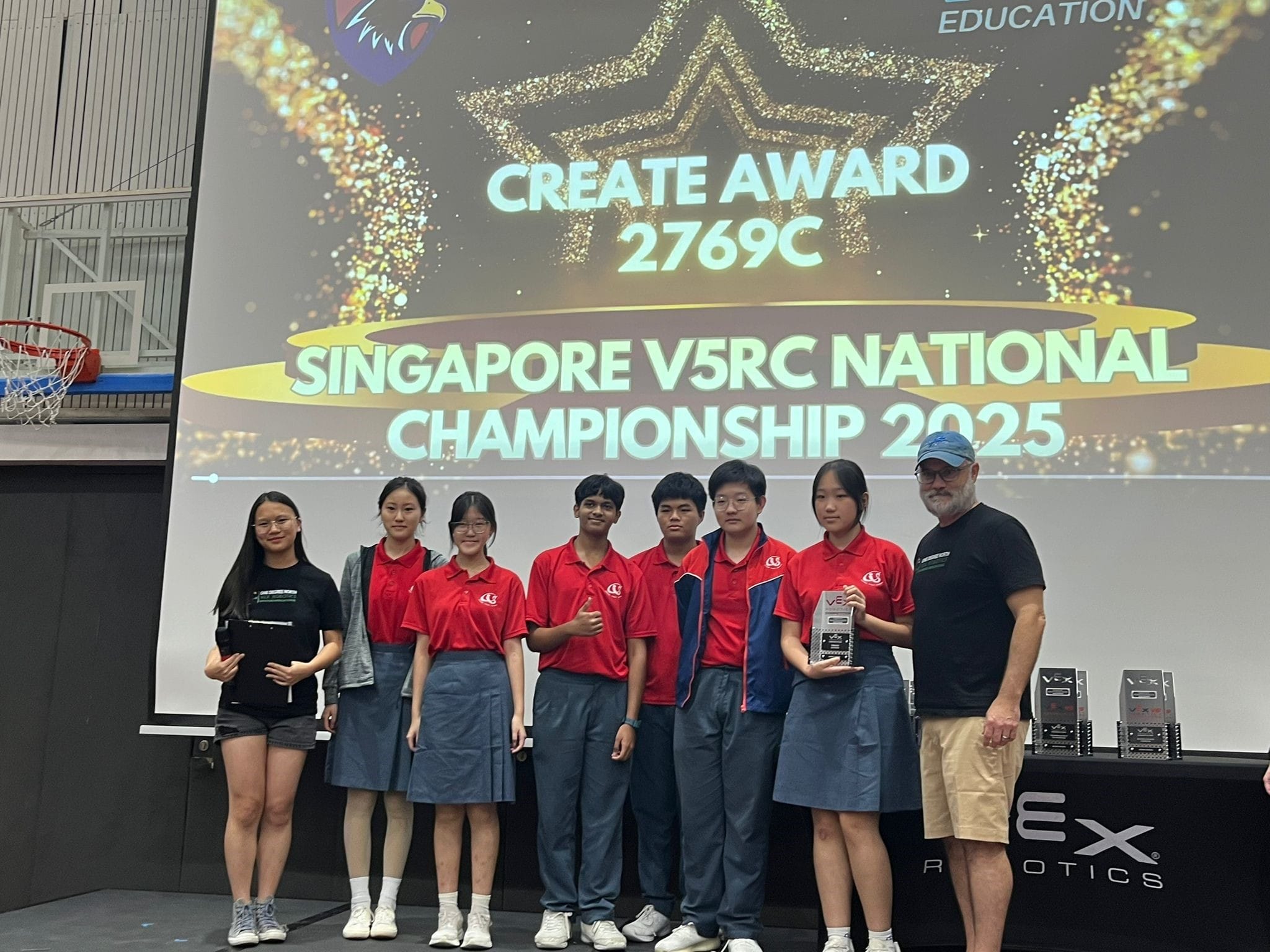 Seven people pose on stage at the Singapore V5RC National Championship 2025, with a Create Award 2769C screen behind them.