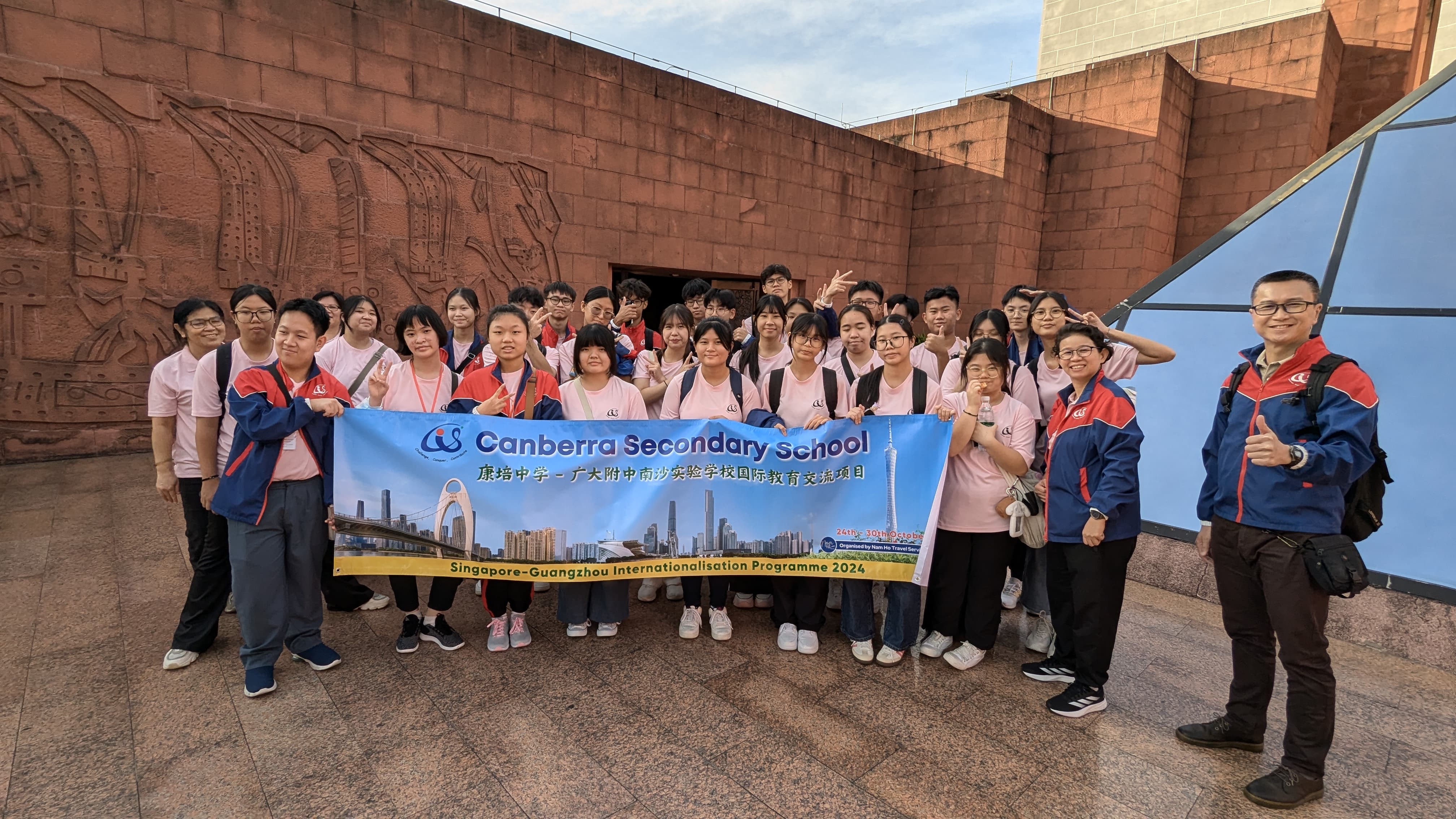 A large group of students and teachers holding a Canberra Secondary School Singapore-Guangzhou 2024 banner outdoors.