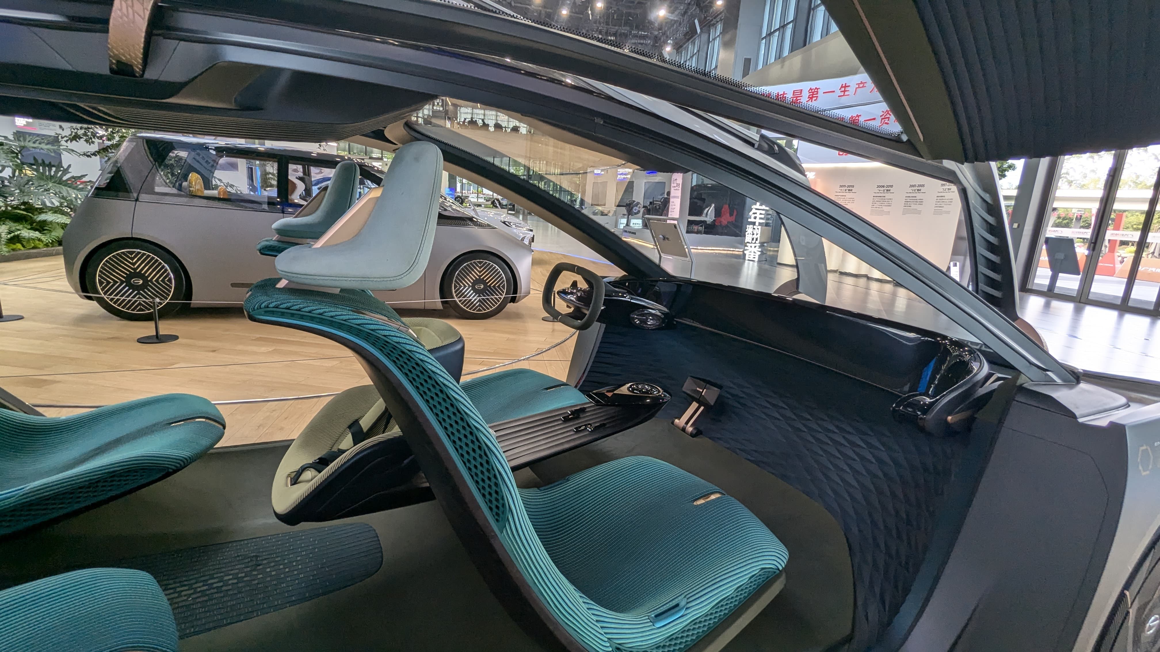Interior of a concept car with teal ribbed seats and minimalist dashboard, displayed at an auto show.