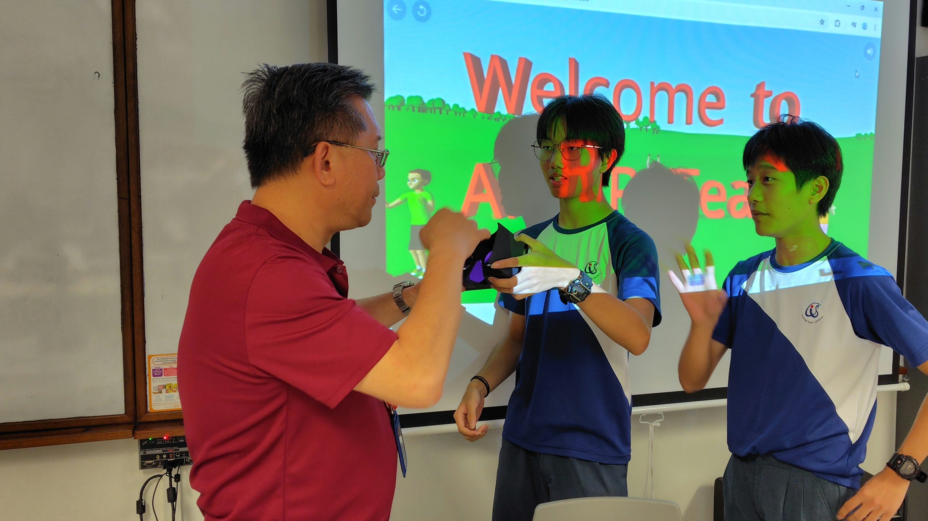 Three people stand before a projected screen showing a Welcome screen, with two students in blue uniforms and an adult in red.
