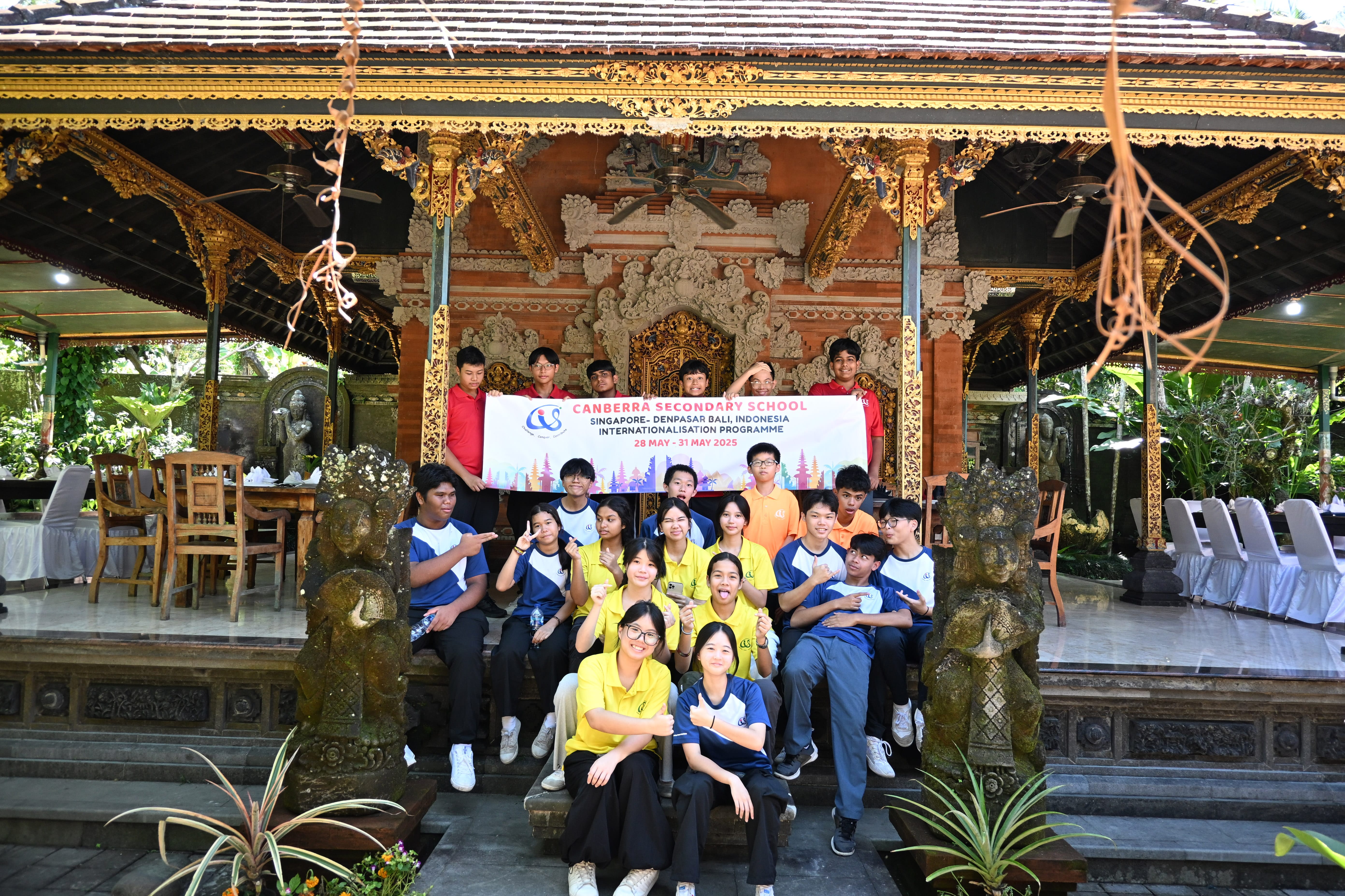 Group of students on temple steps holding a Canberra Secondary School trip banner under ornate pavilion.