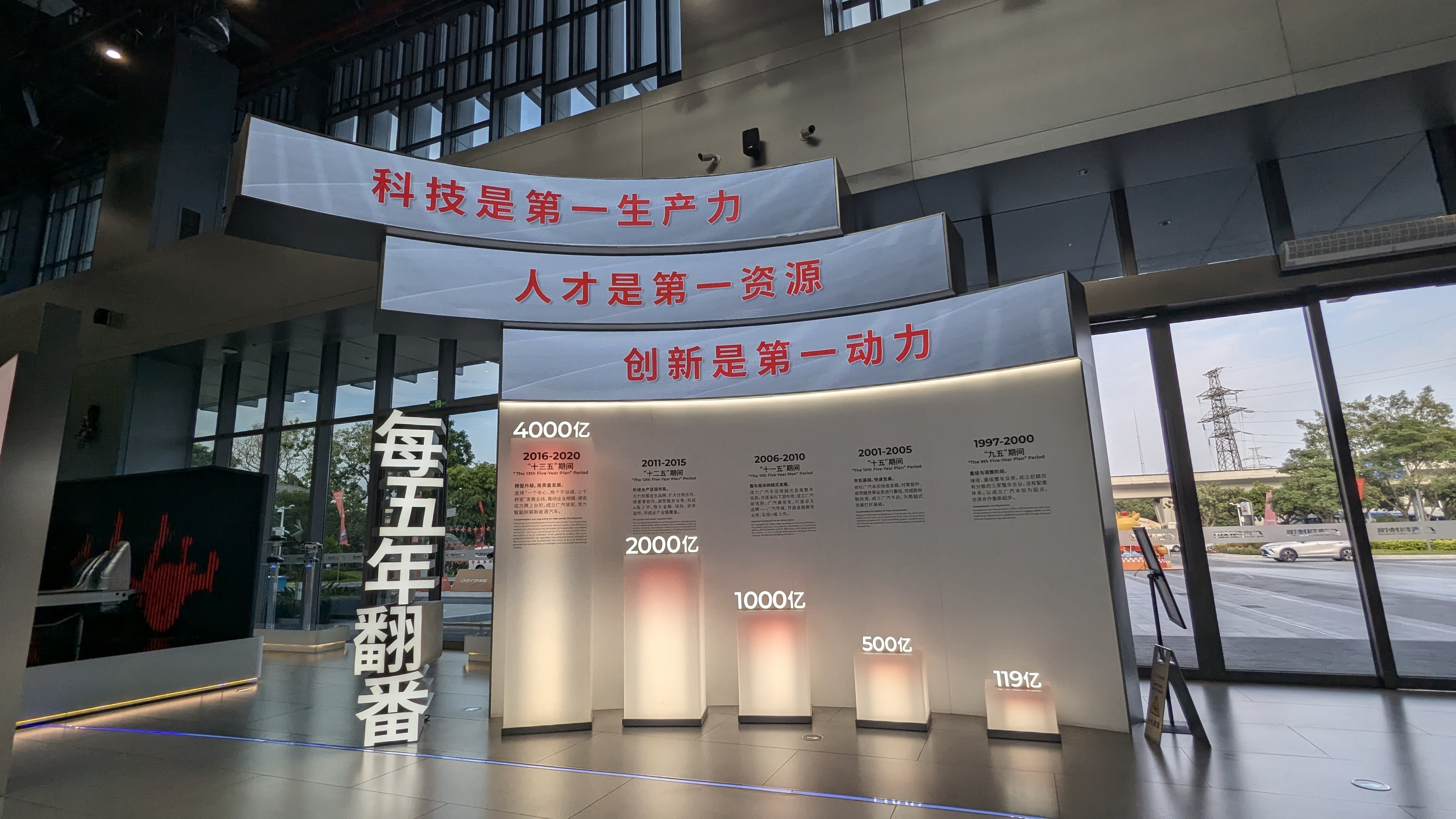 Indoor exhibition display with Chinese text banners and illuminated columns showing increasing numerical milestones from 1997 to 2020.