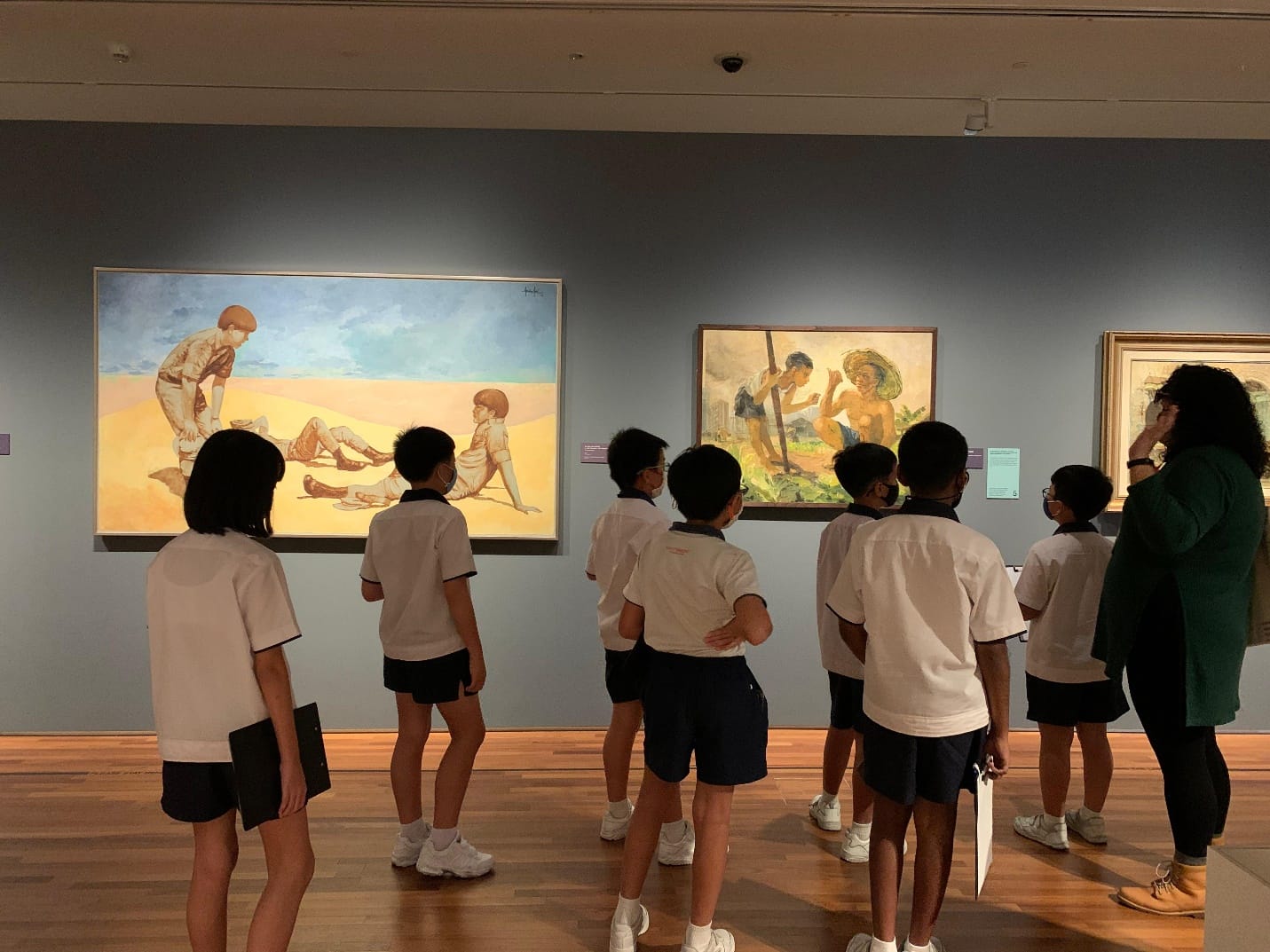 Students view paintings on a gallery wall