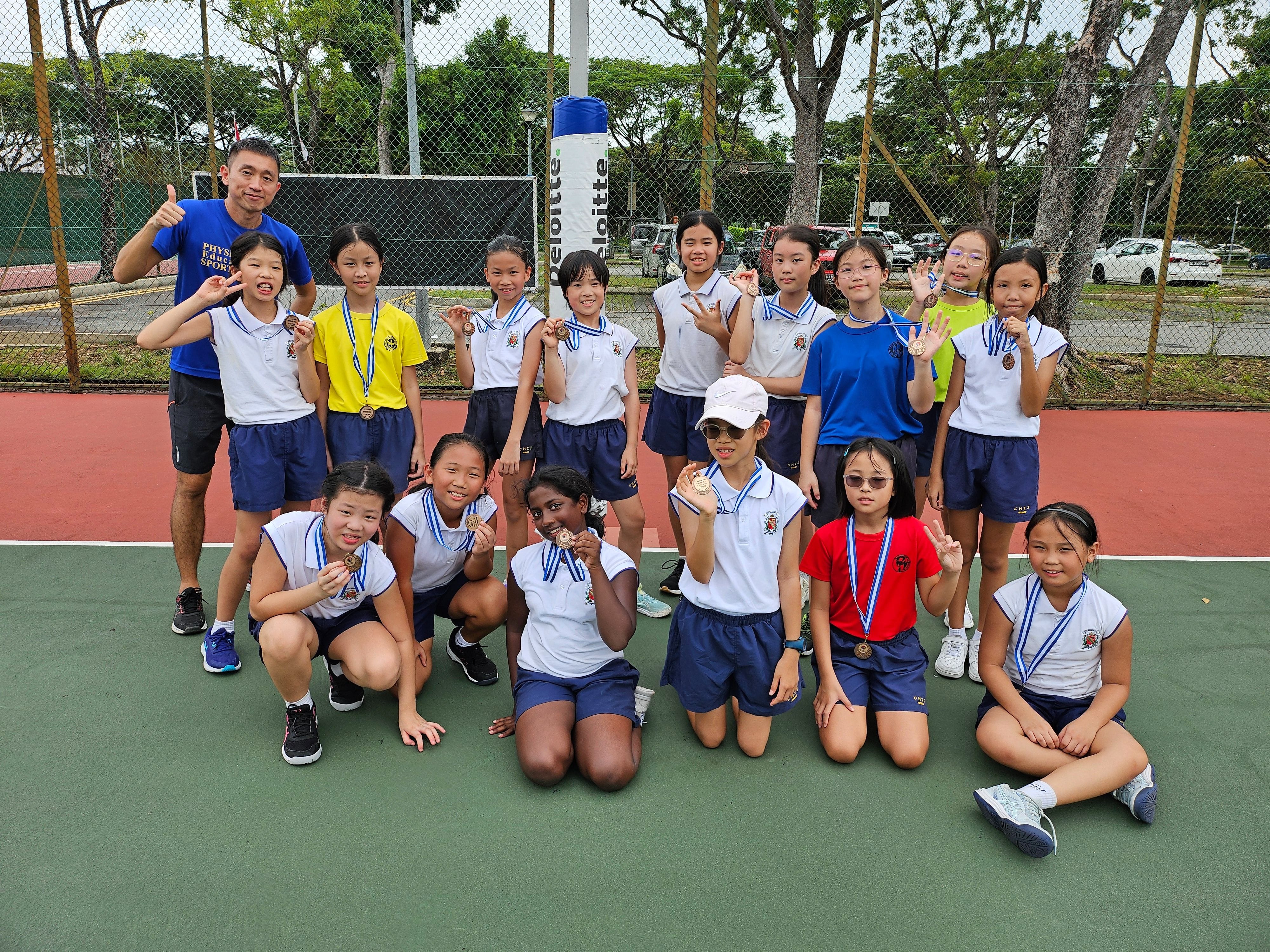 A group of young girls in school uniforms proudly display medals.