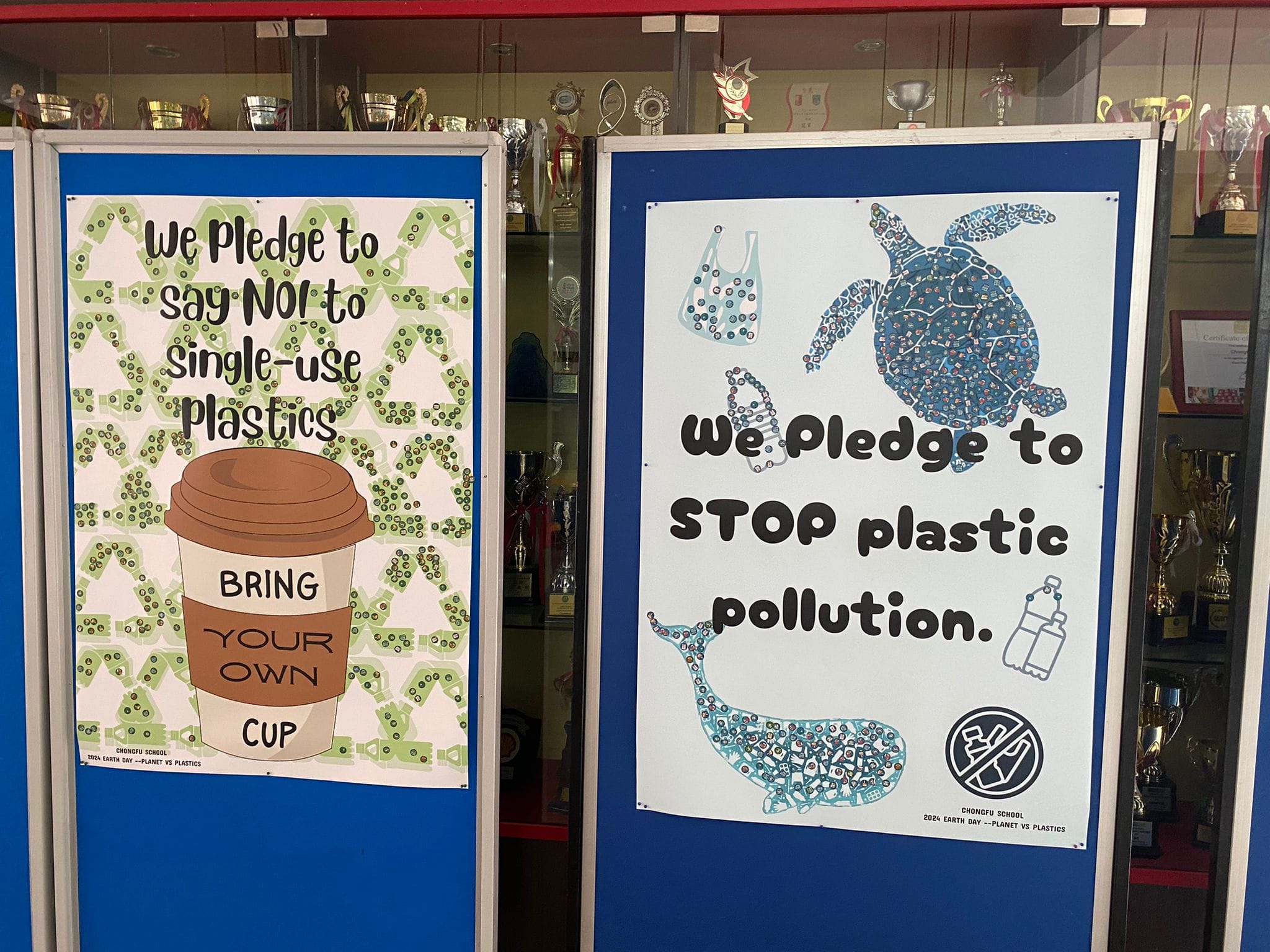 Two school posters pledging to say no to single-use plastics and stop plastic pollution, displayed on a blue board.