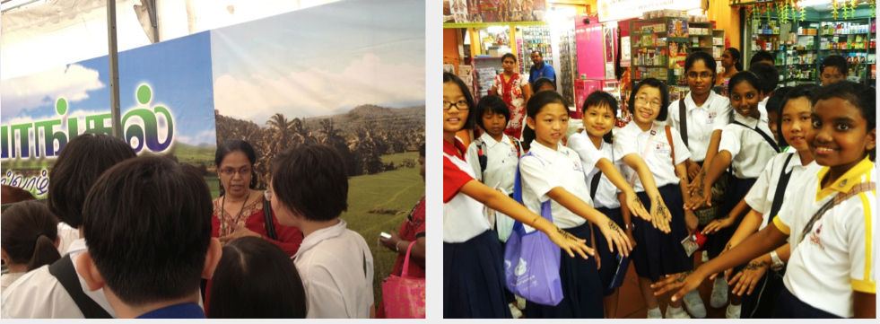 Students in school uniforms on a field trip, one group by a Tamil display, another showing henna-decorated hands in a shop.