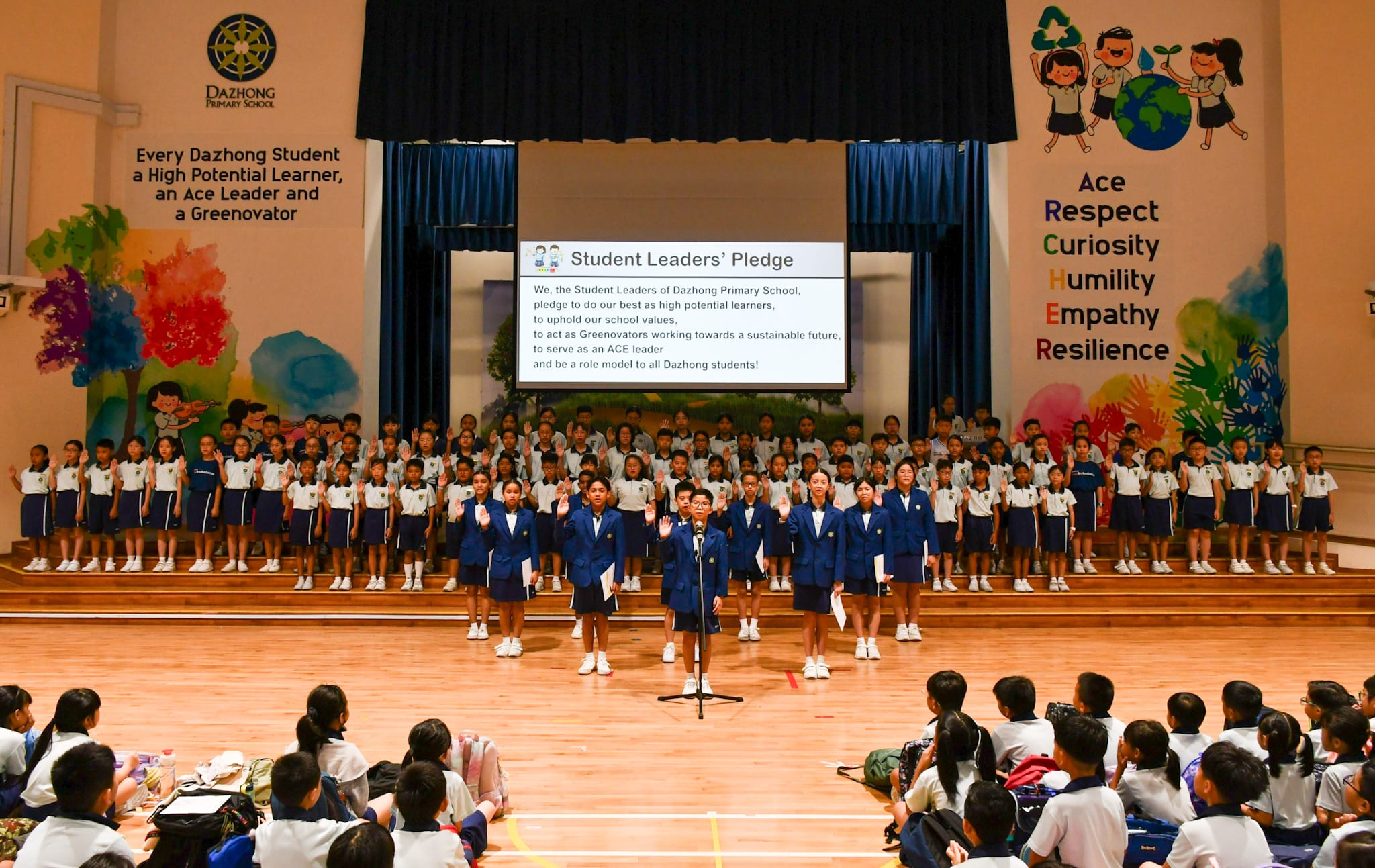 Students in uniforms recite the Student Leaders' Pledge at Dazhong Primary School assembly hall.