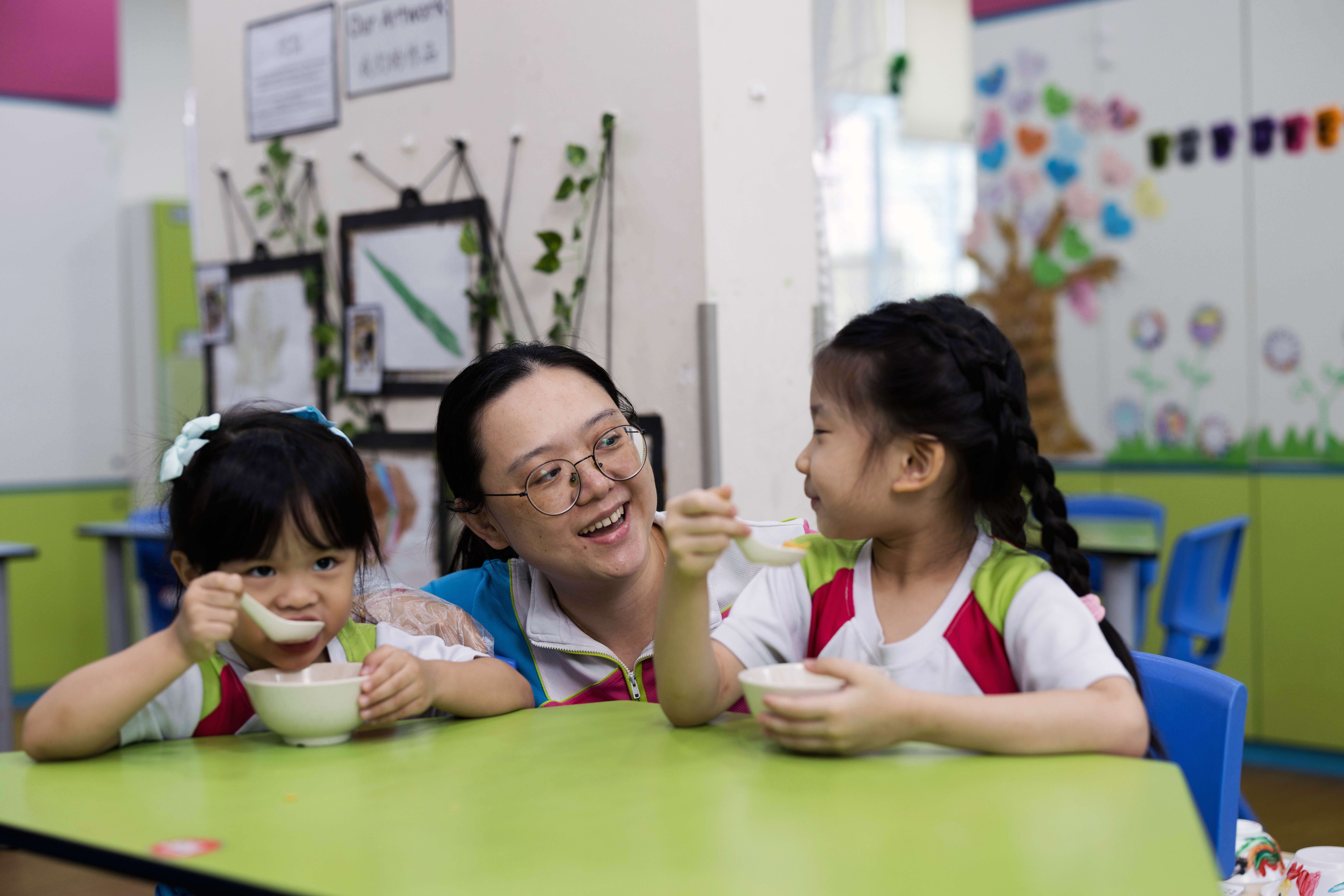 Teachers chatting with children over lunch
