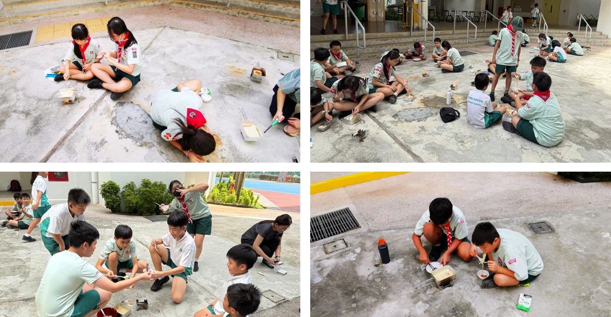 Groups of school children in uniforms with red scarves sit on outdoor pavement eating meals from containers.