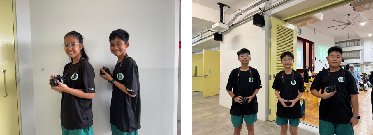 Five students in matching black Media shirts and teal shorts hold cameras indoors, smiling at the camera.